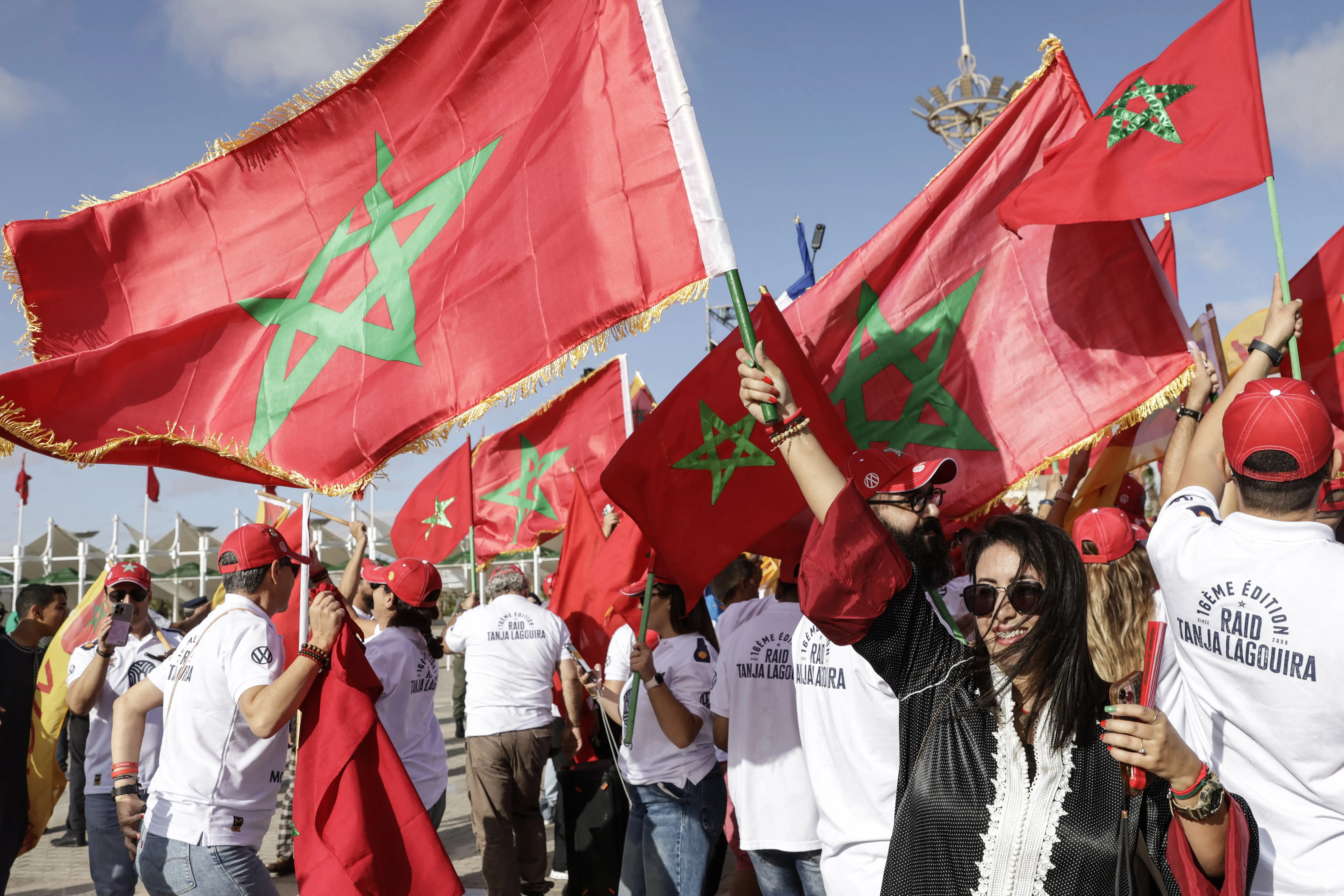 People wave Moroccan flags in a crowd.