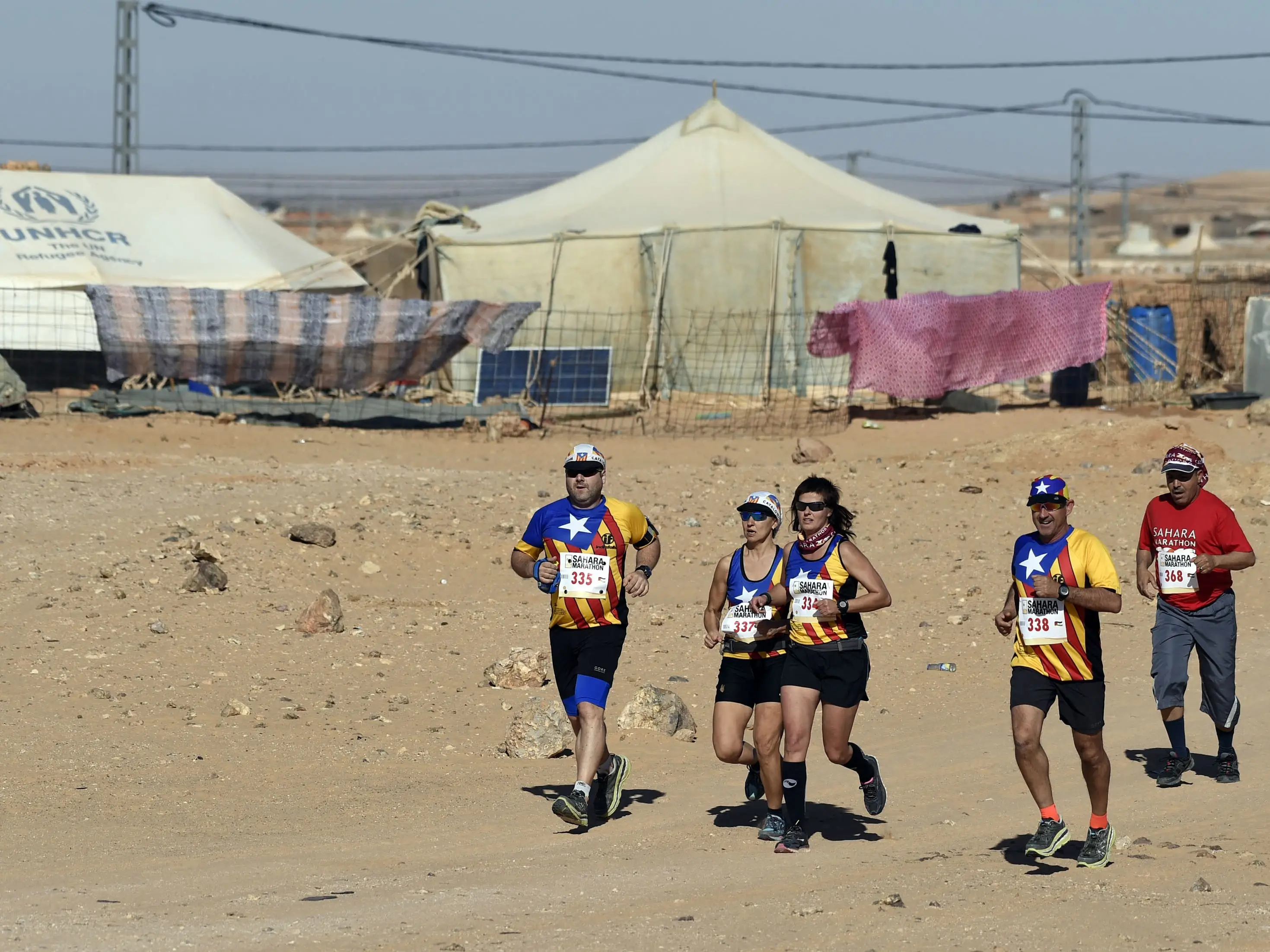 Competitors run during the 16th Sahara Marathon on February 23, 2016, with refugee camps in the background.