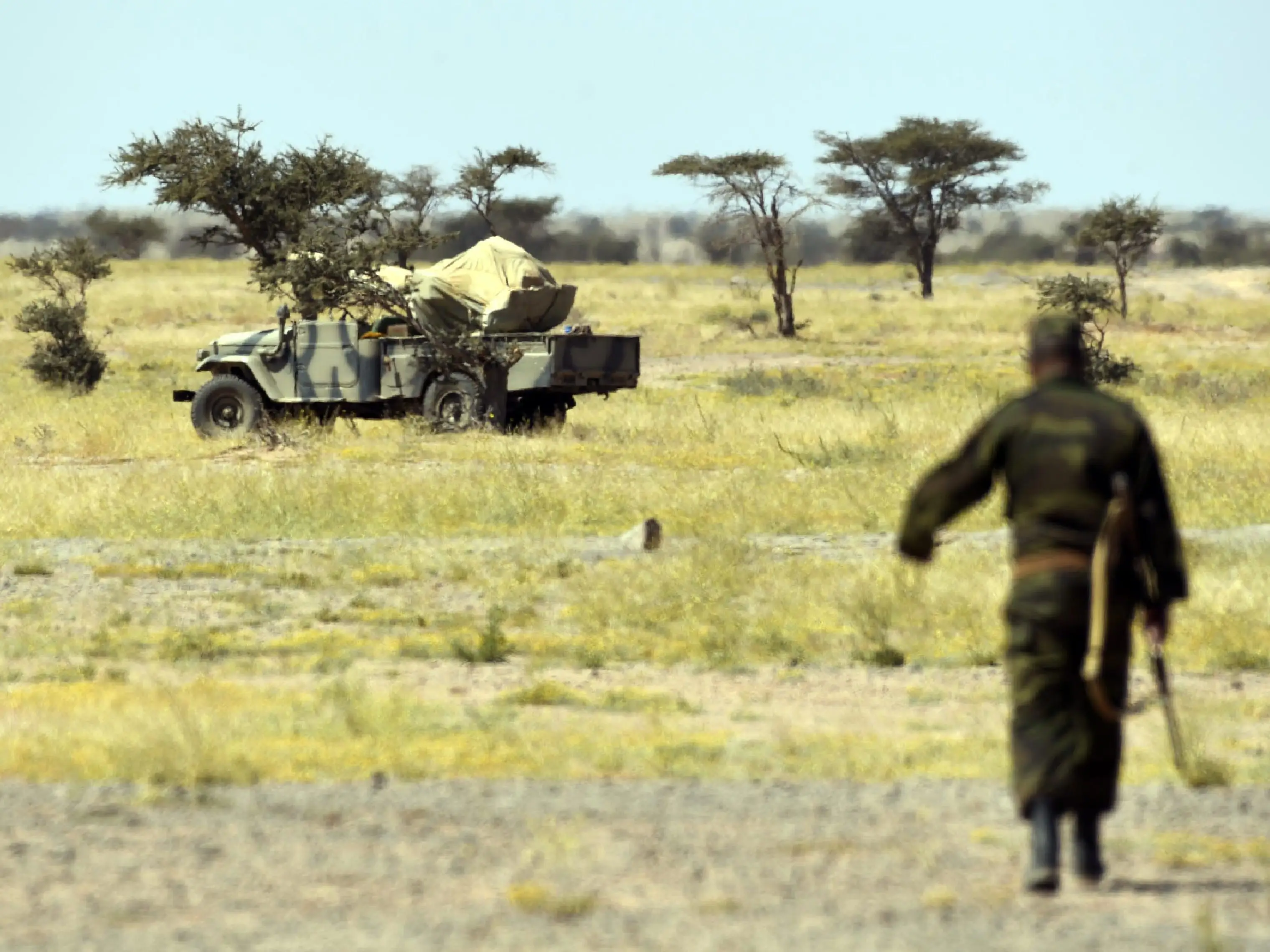 A member of the Polisario Front stands guard near a military vehicle.