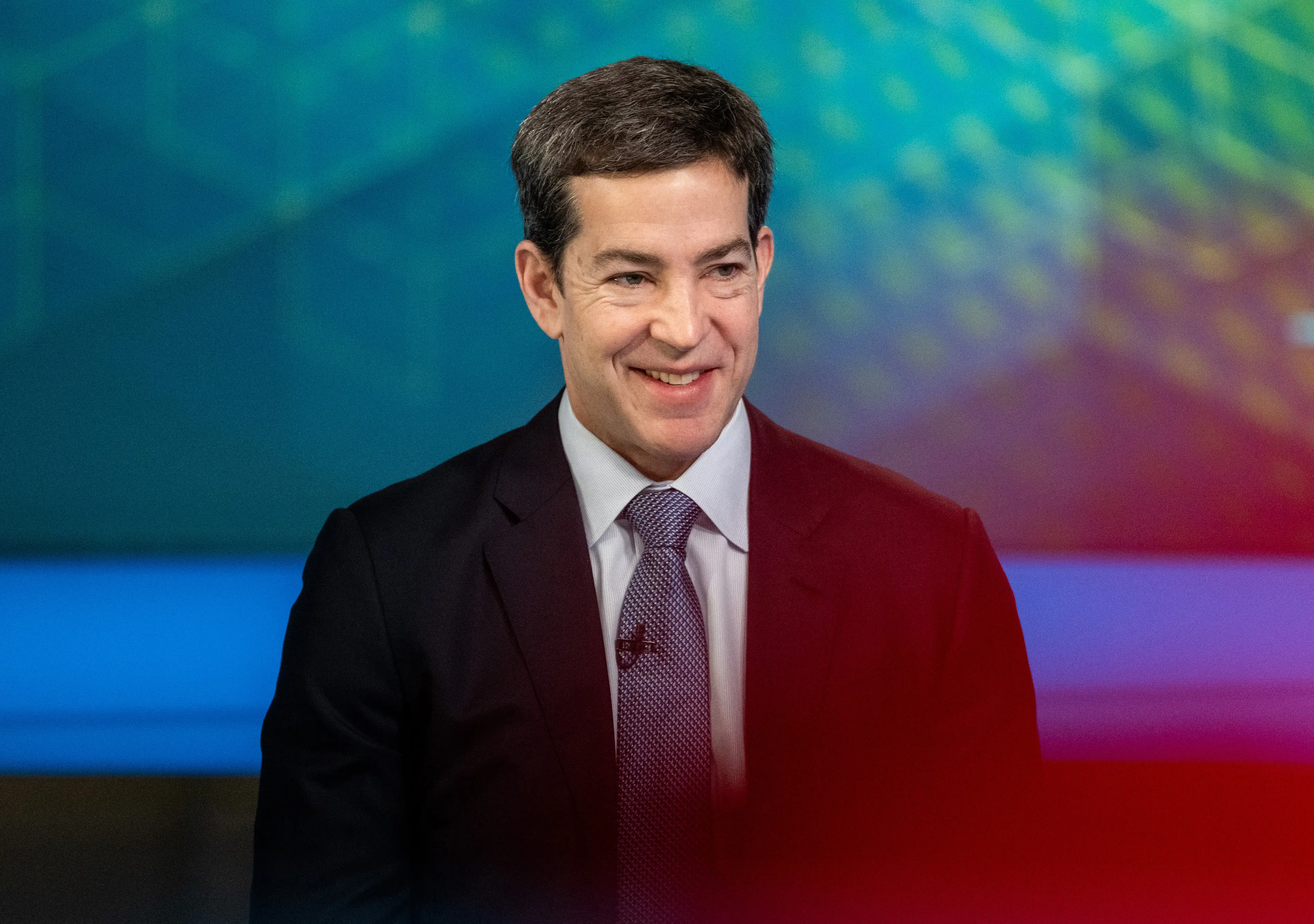 Todd McKinnon, the CEO of Okta, is onstage in a suit with a blue tie.