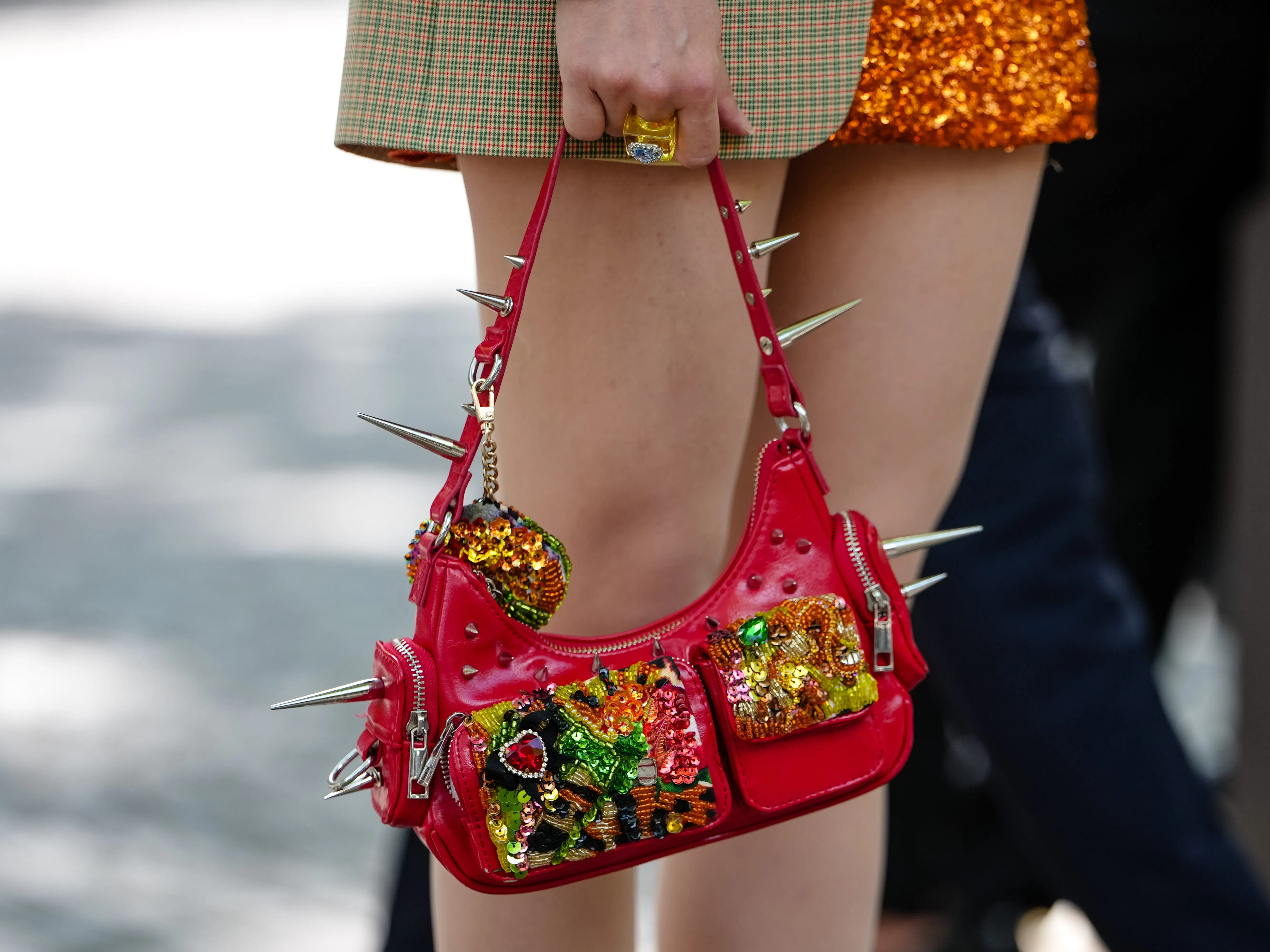 A pink purse with lots of embroidery and spikes on the strap.