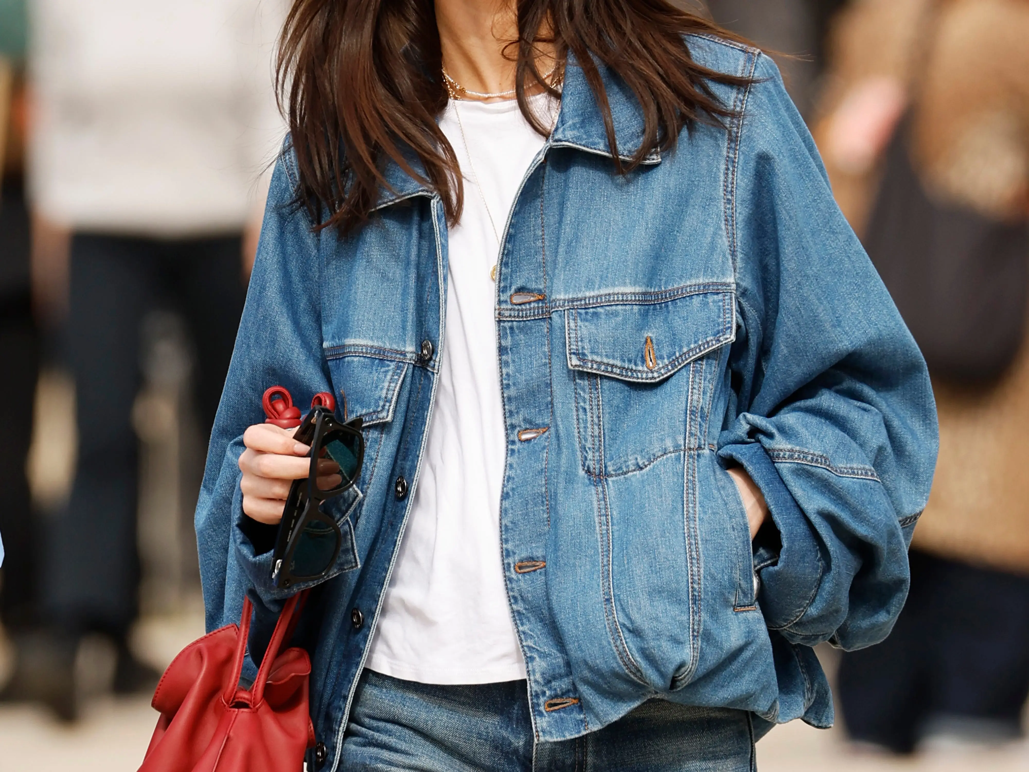 A woman wearing an oversize denim jacket with a white T-shirt underneath.