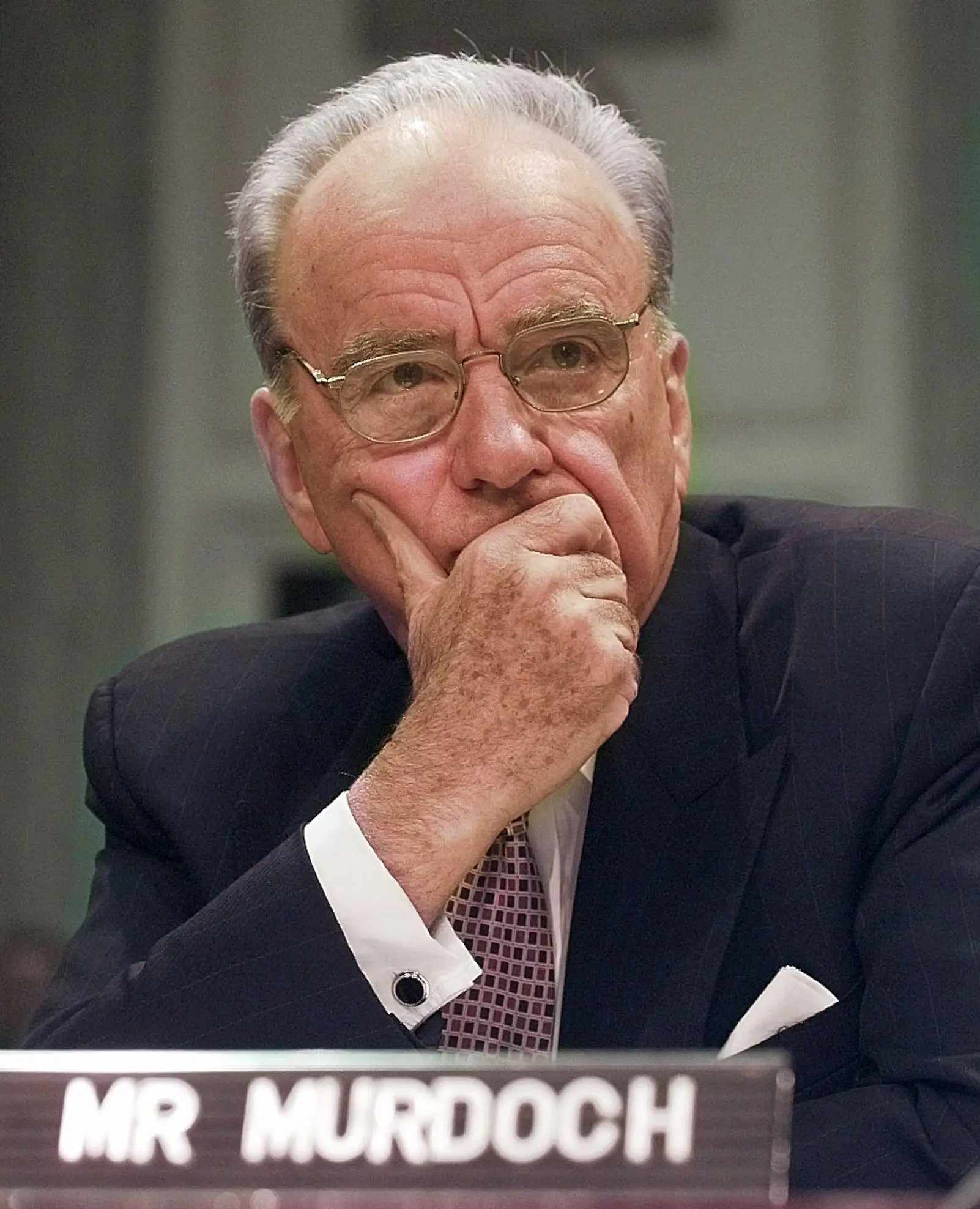 Rupert Murdoch sitting with hand covering mouth