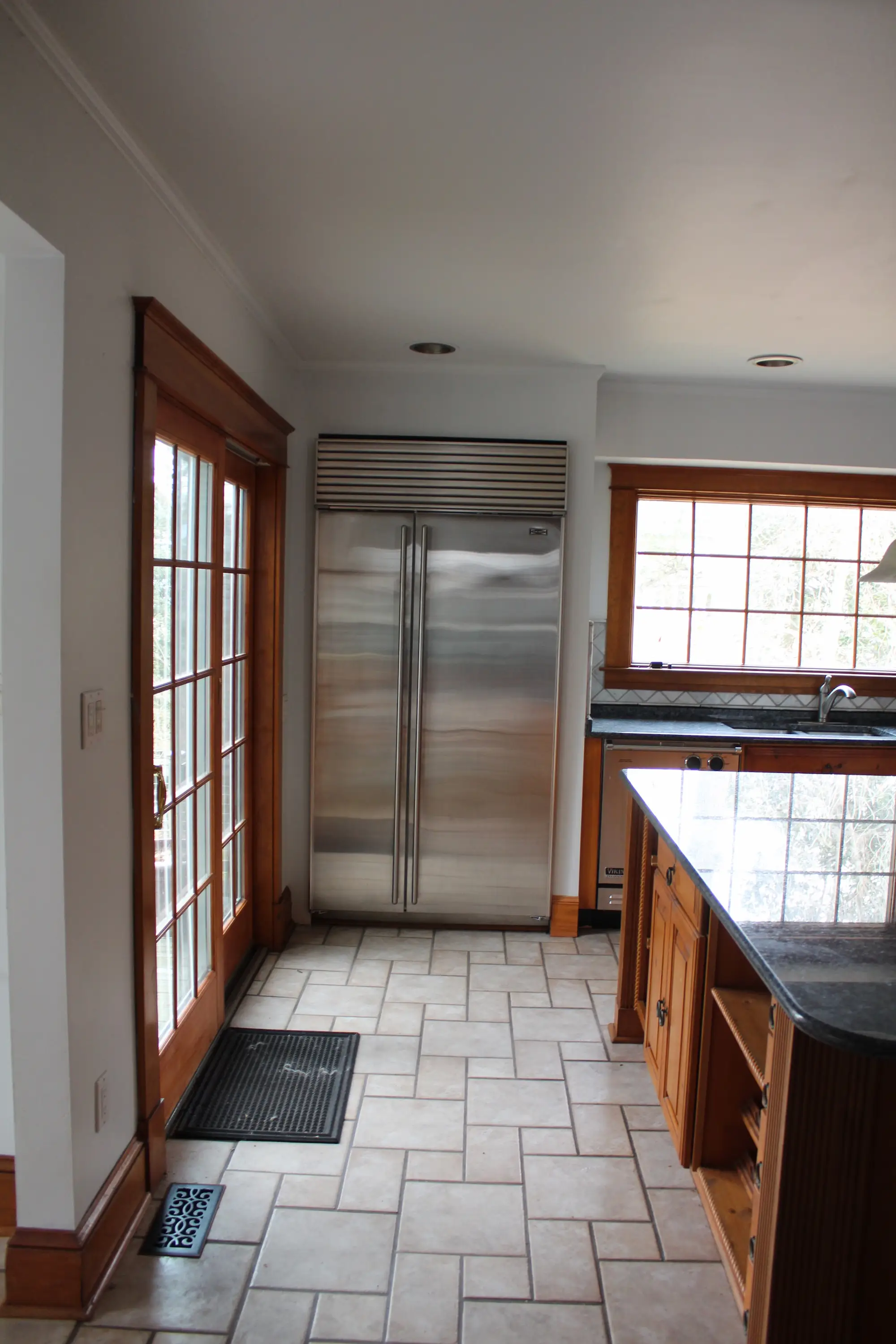 A kitchen with a doorway leading outside on the left and a refrigerator.