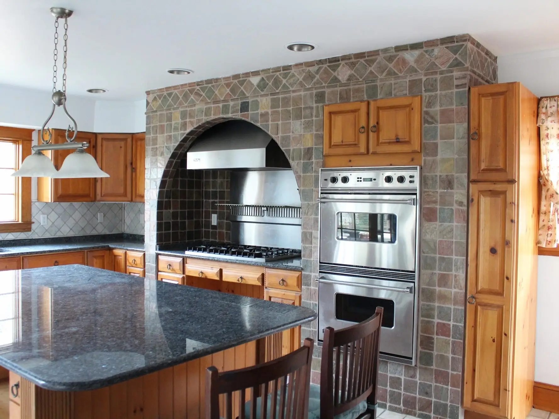 A kitchen with an arched, stone wall above the stove.
