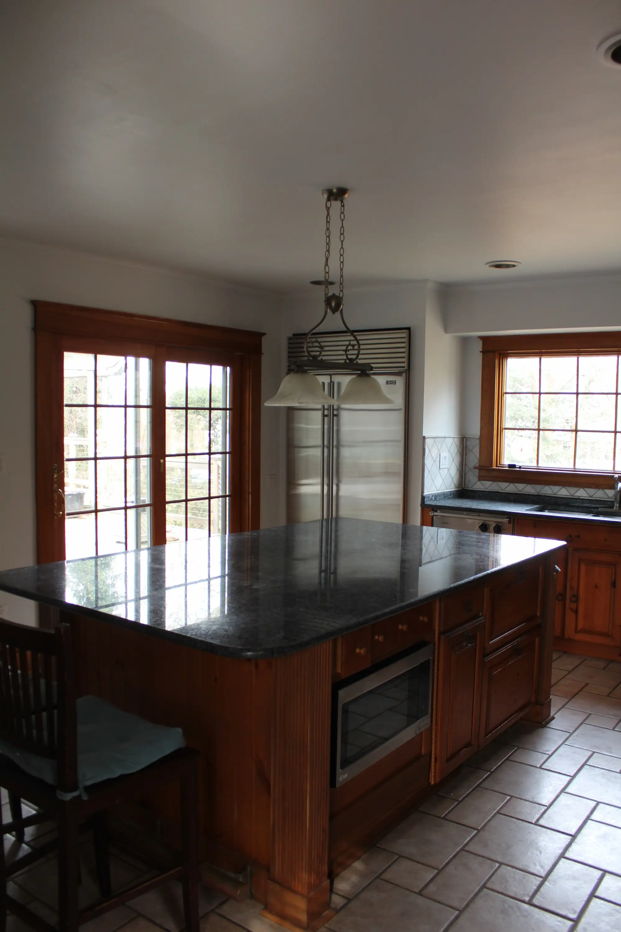 A kitchen with a large island that has a dark countertop.
