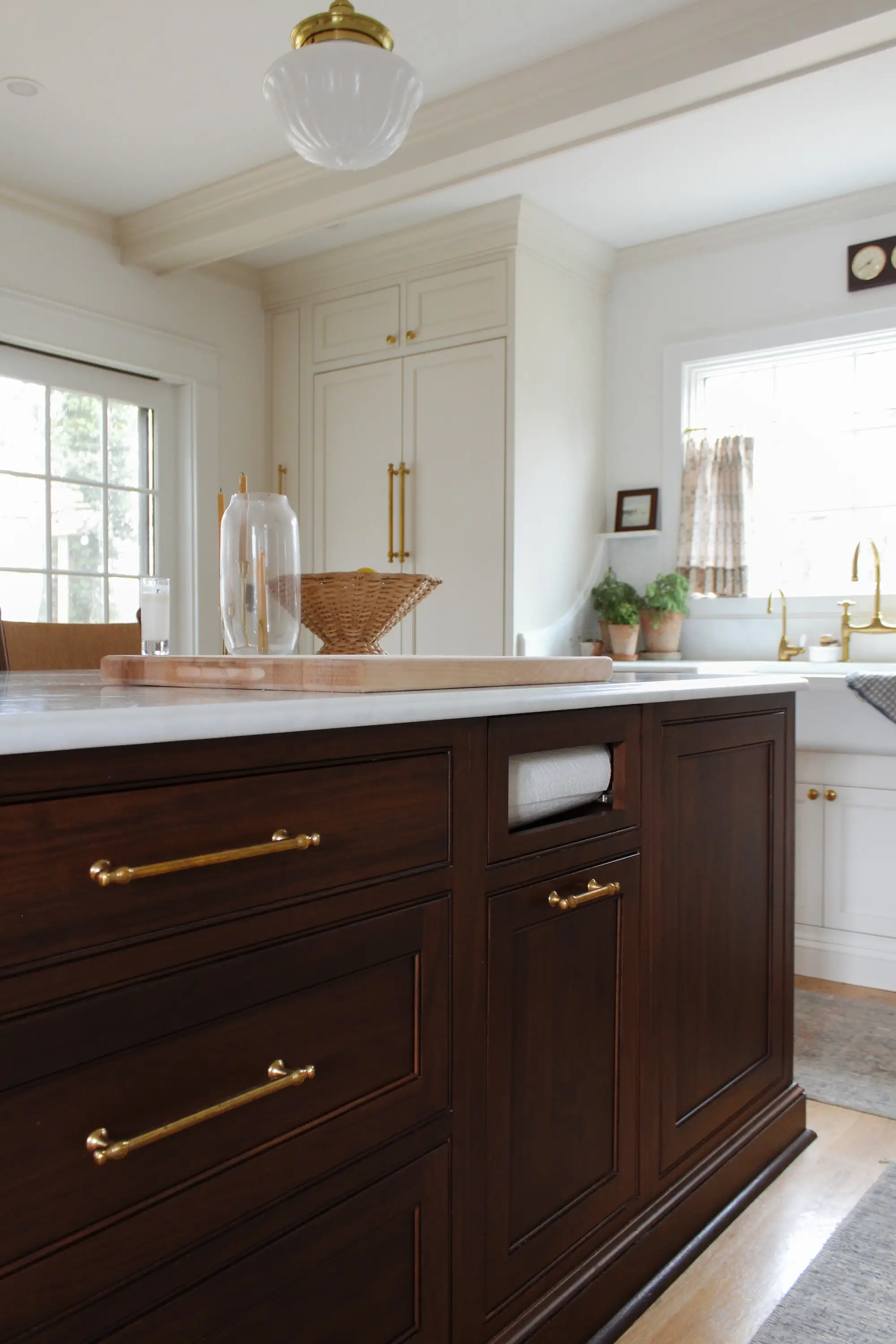 A kitchen with white cabinetry and a large island with wood cabinetry.
