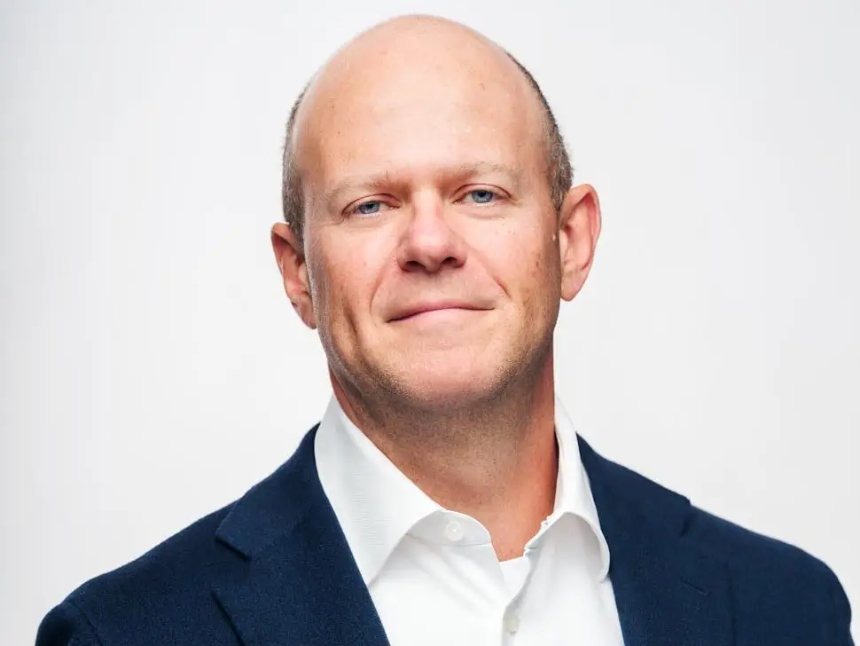 Dmitry Balyasny smiles in front of a white background