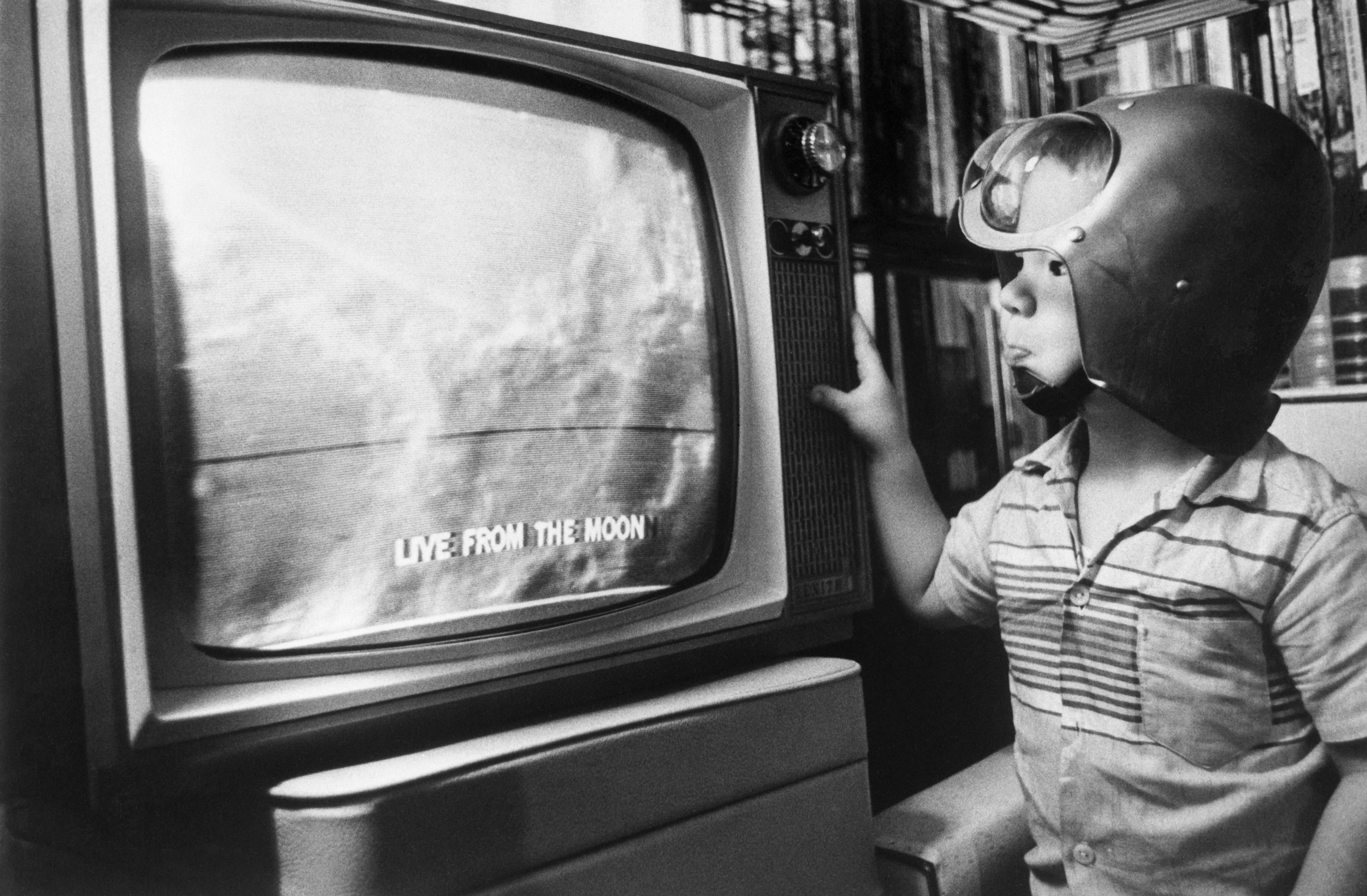 Jay Bodnar watches as the first televised pictures of the moon's surface are beamed back to earth in detail. The Ranger 9 unmanned probe shows Americans an unprecedented view of the surface, and Jay wears his space helmet in celebration of the live event.