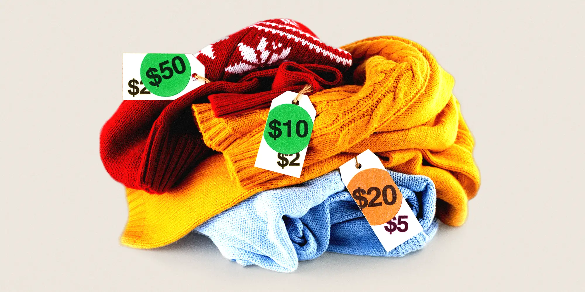 Pile of sweaters with visibly altered price tags, showing a wide range of prices from $2 to $50.