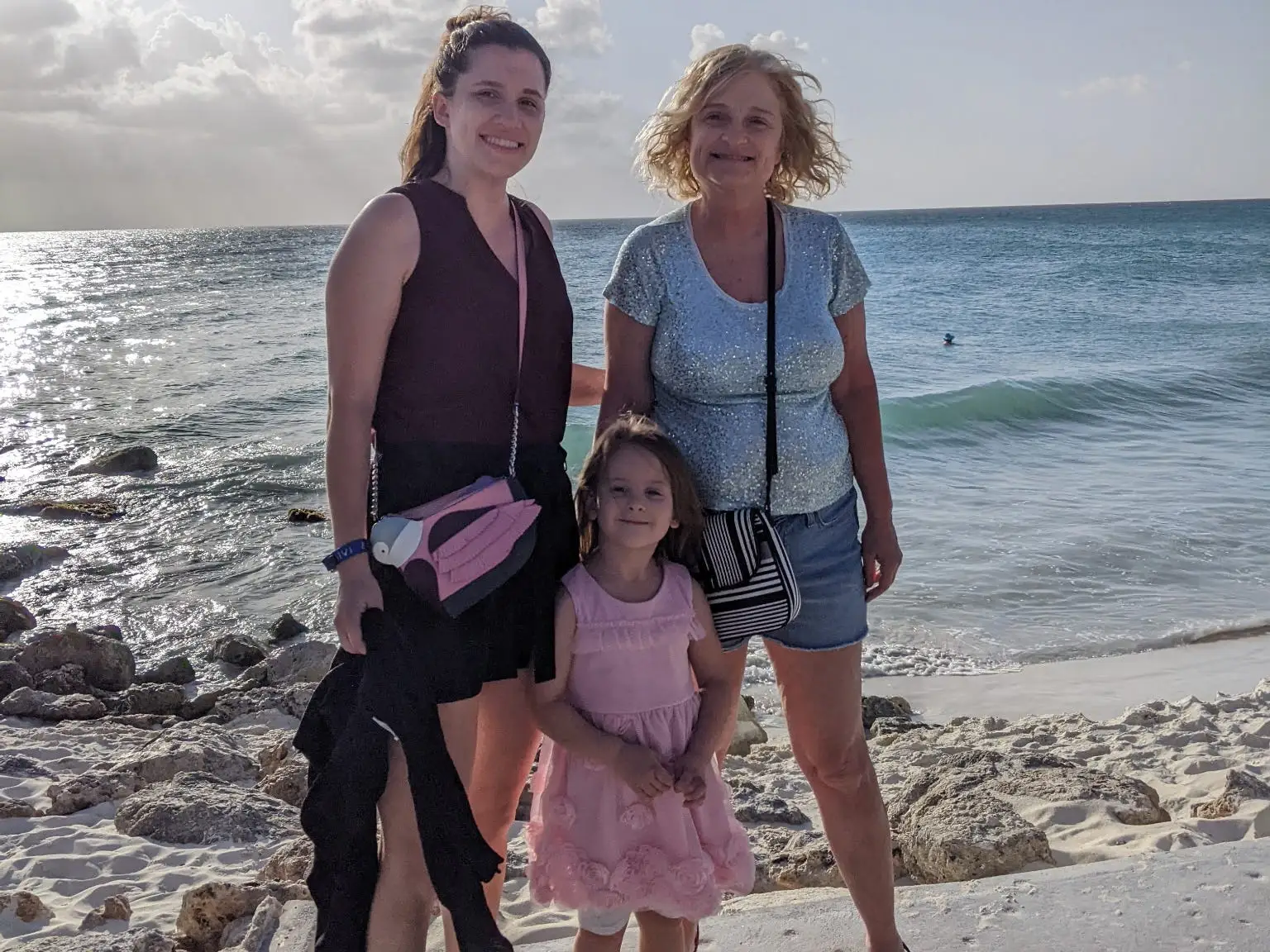 A grandmother, granddaughter, and daughter in front of the ocean.
