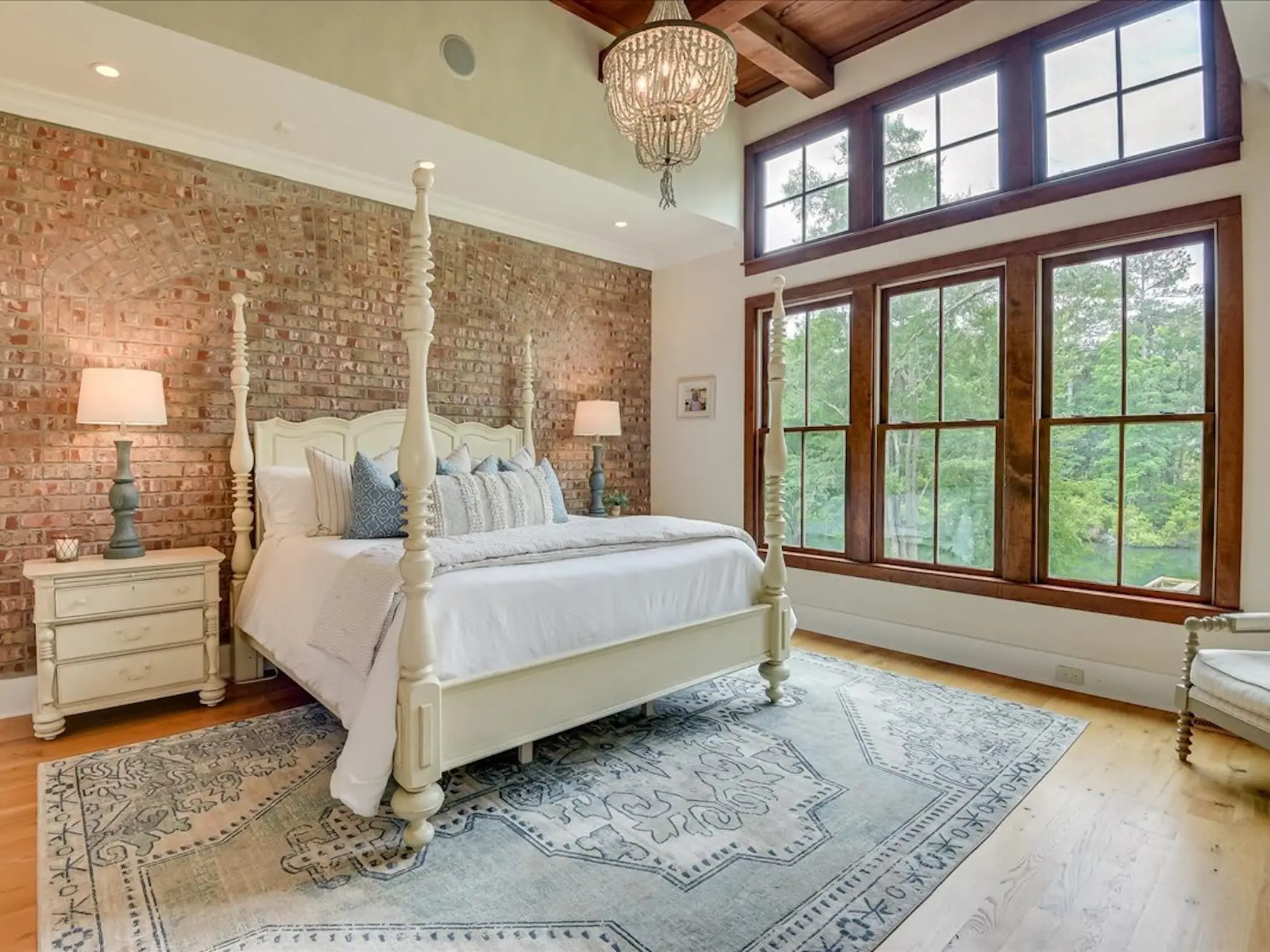 A bedroom with a brick wall and a large four-poster bed.