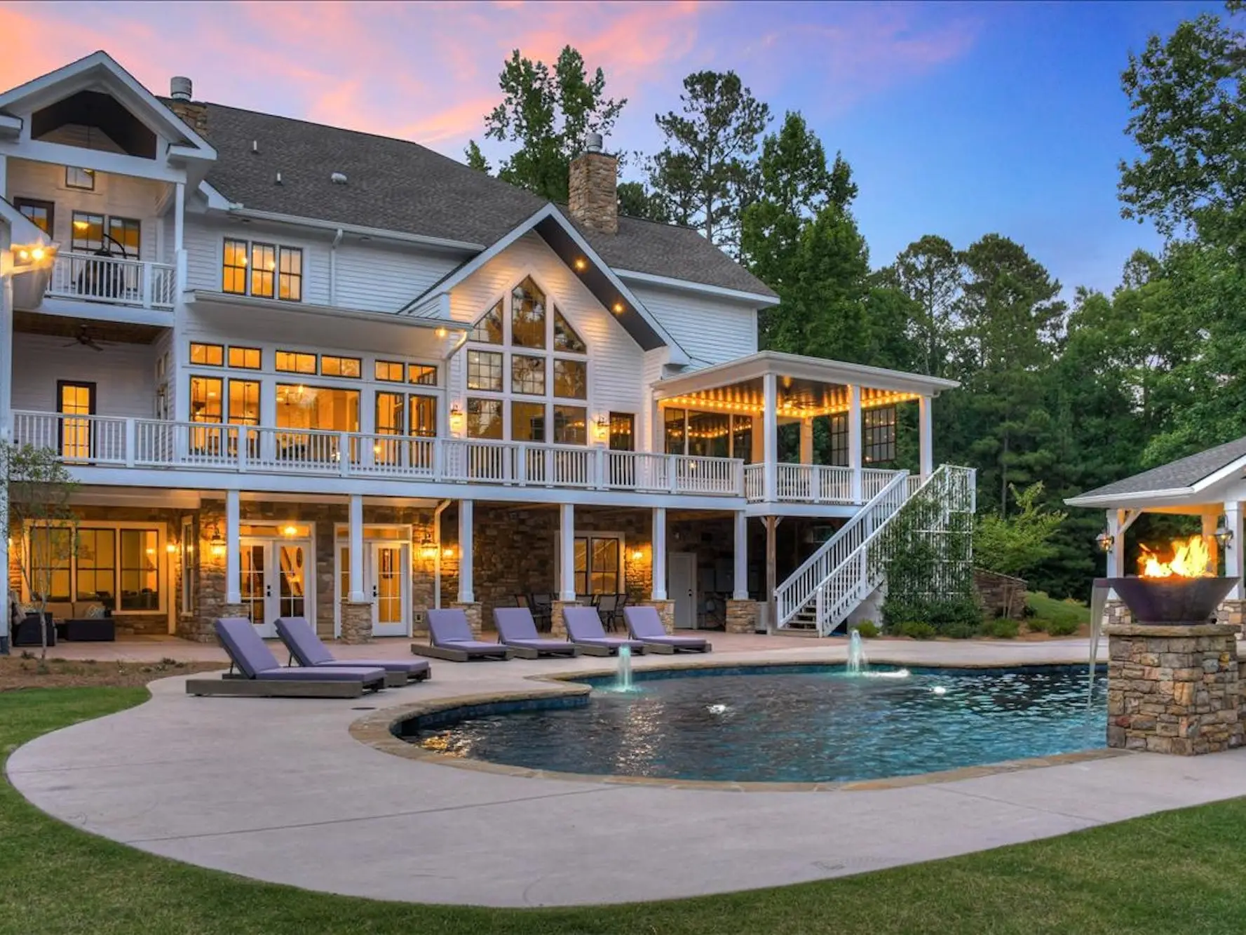The back of a white home with a large pool in front of it.