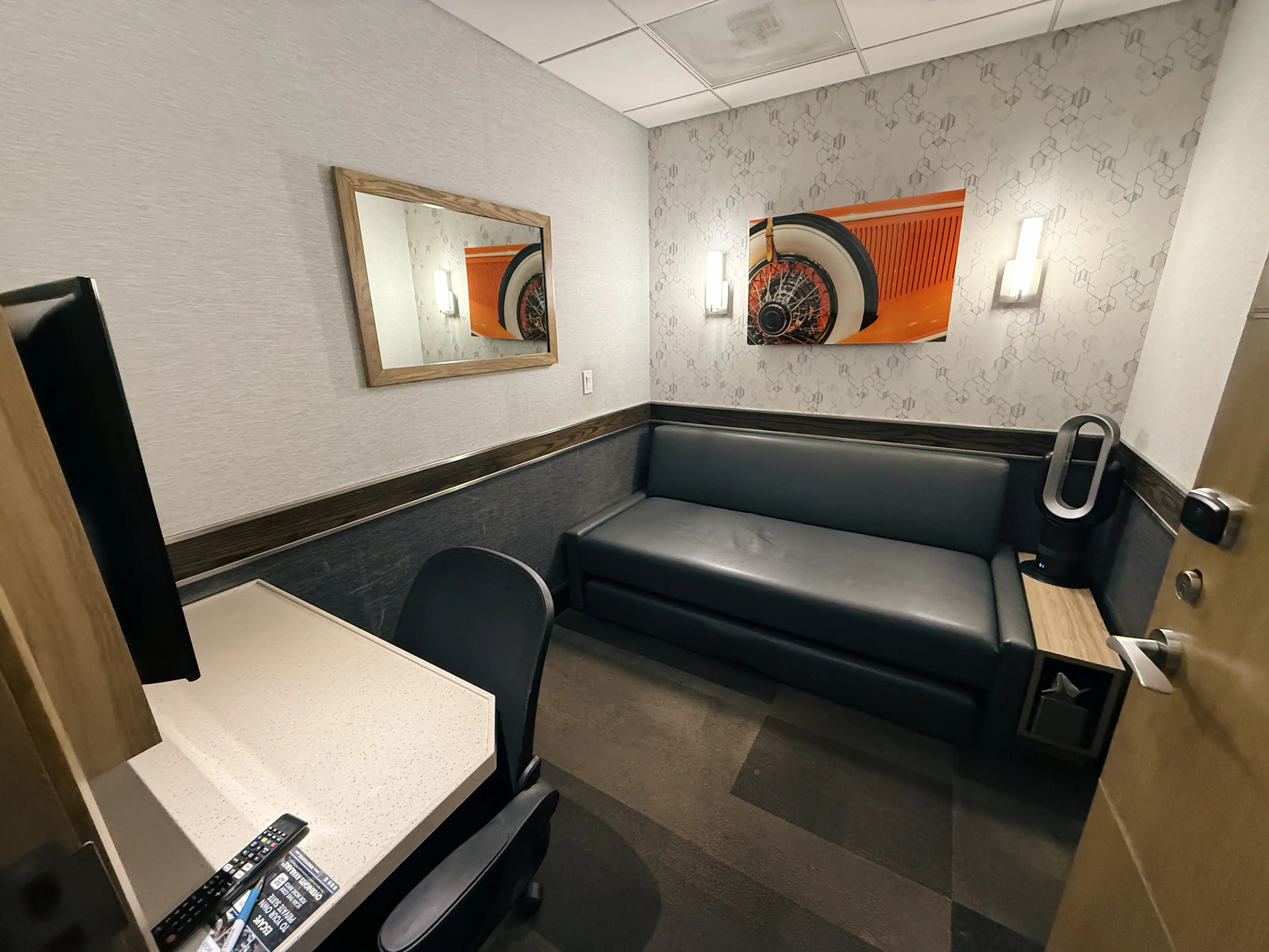 Interior of Minute Suites CLT Gold Rush Room with desk, bed/couch, minimal wall art