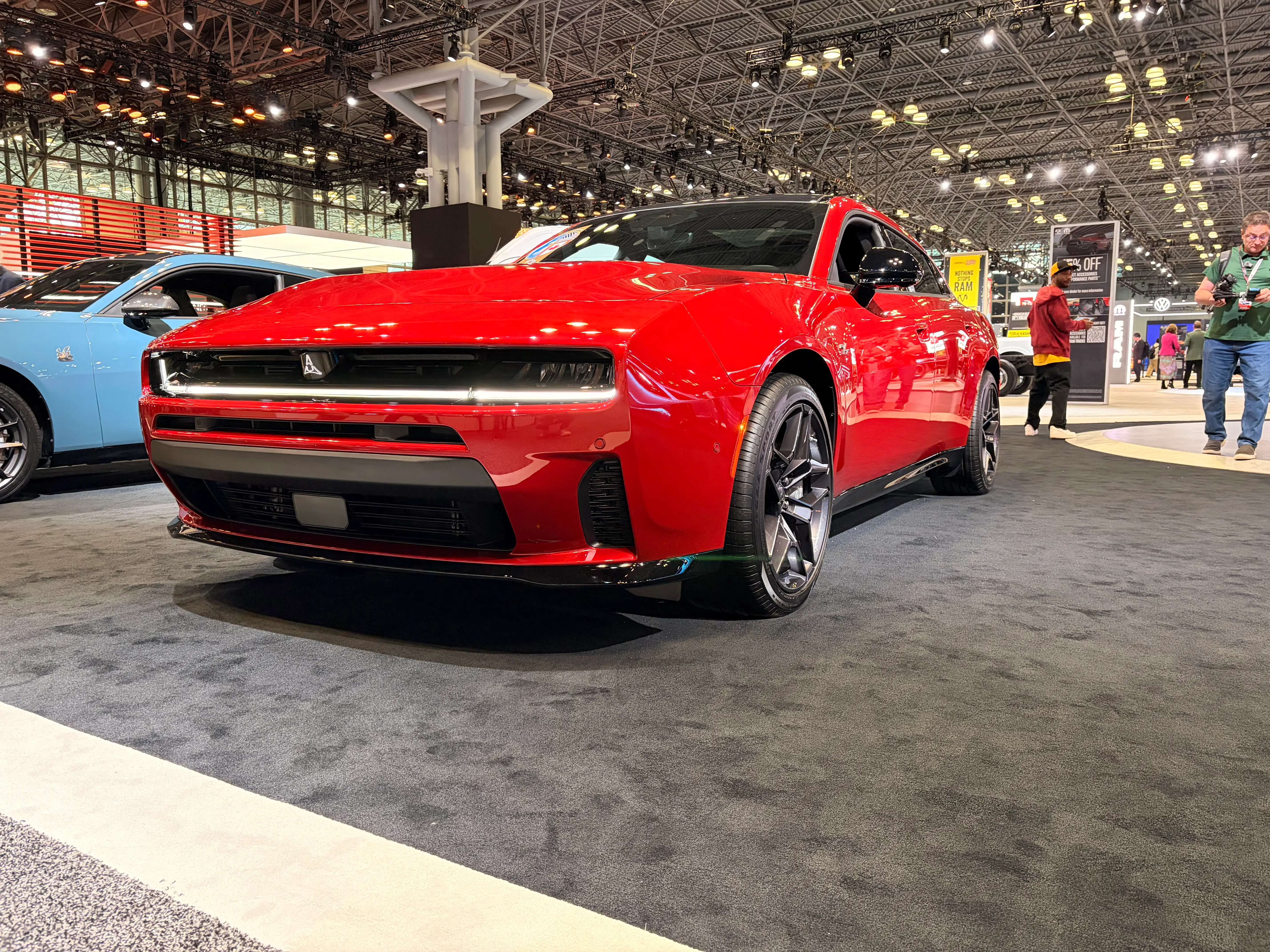 A red 2026 Dodge Charger sedan is parked on the carpeted New York Auto Show floor.
