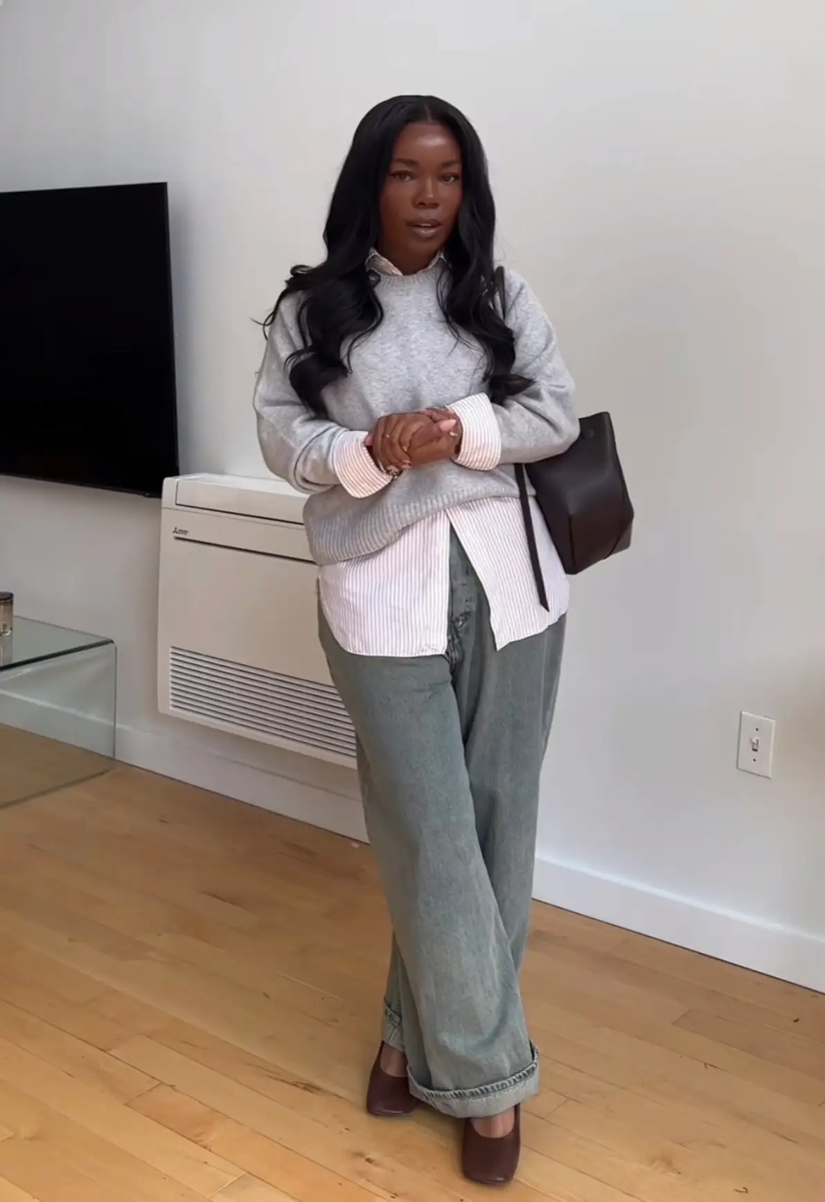 Crystal McDuffy in a work outfit — a gray sweater over a striped collared shirt and faded jeans