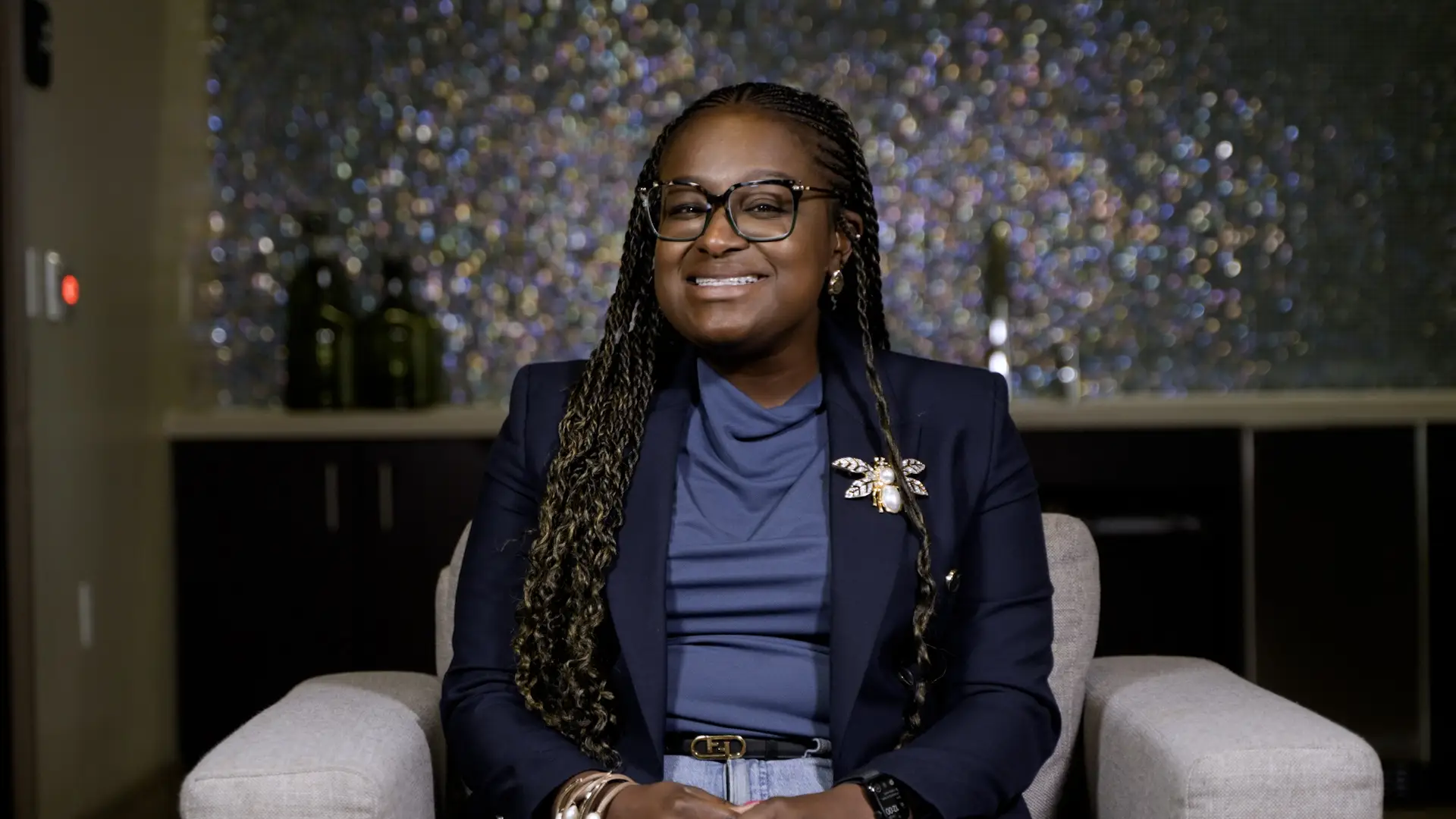 Camille Stewart Gloster sitting in a white chair in a blue shirt.