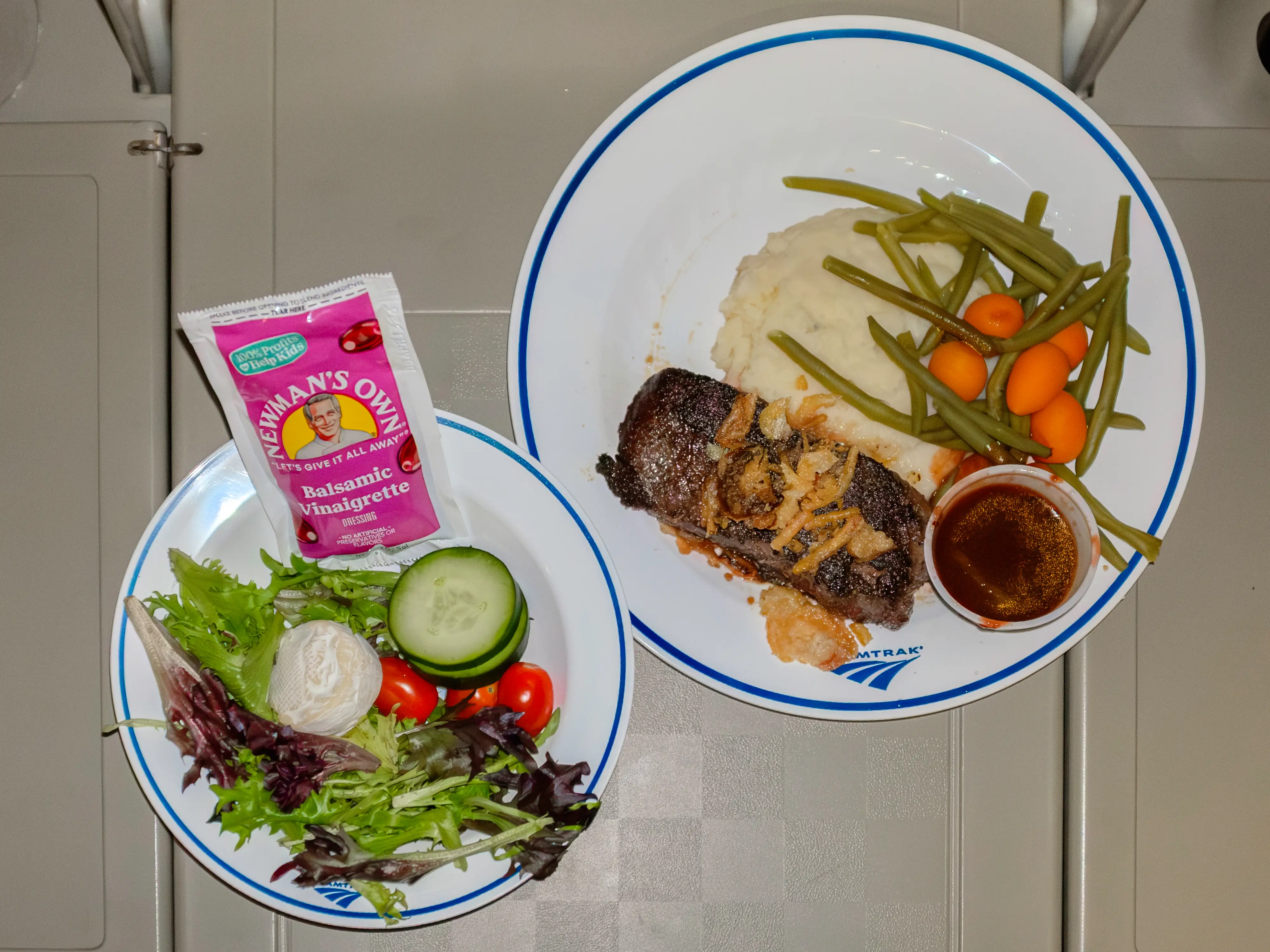 An aerial shot of a salad and steak dish on an Amtrak train