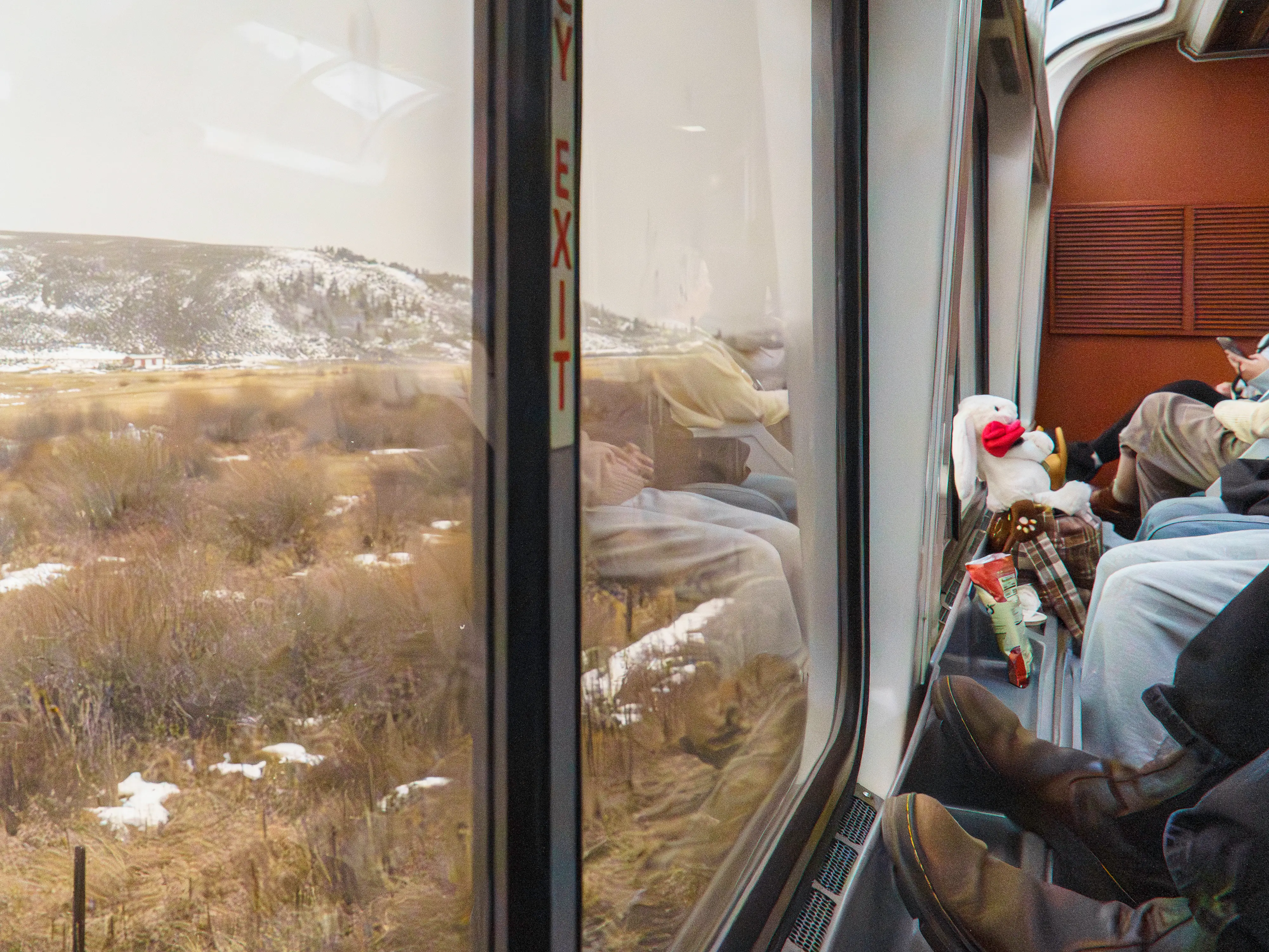 Inside a train car with windows on the left and passengers on the right