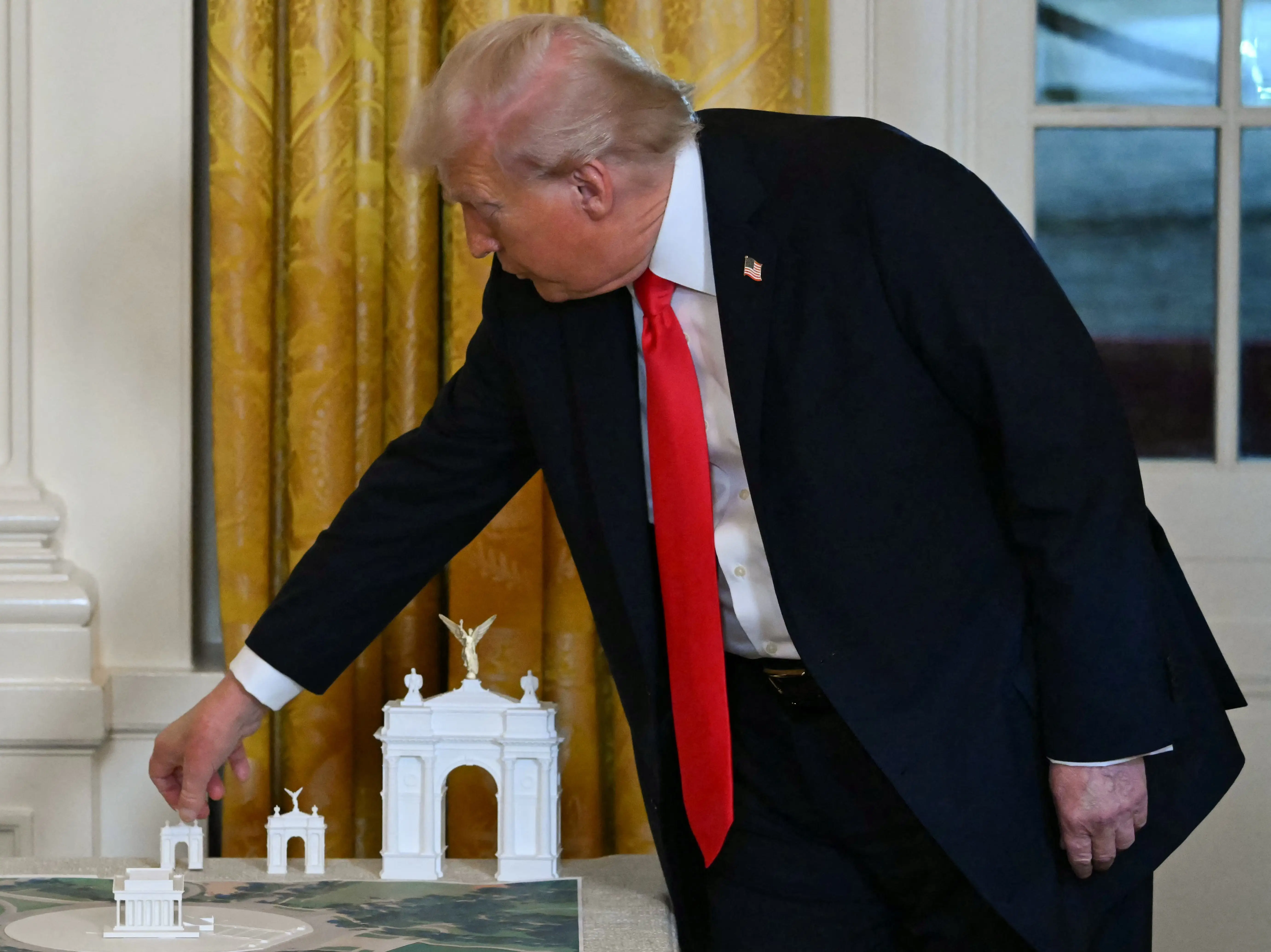 US President Donald Trump stands near models for a proposed 