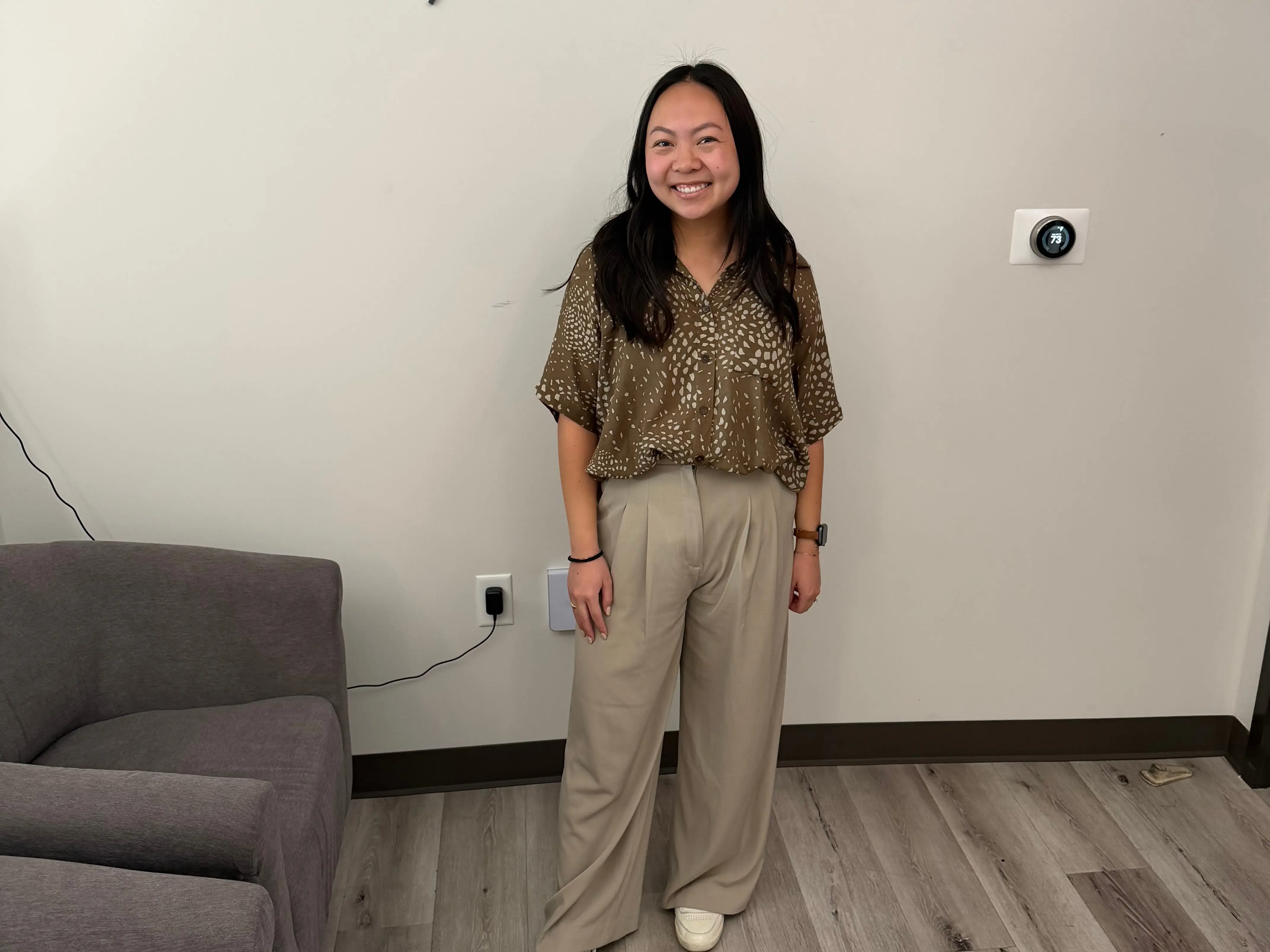 A woman standing in front of a wall with her company logo.