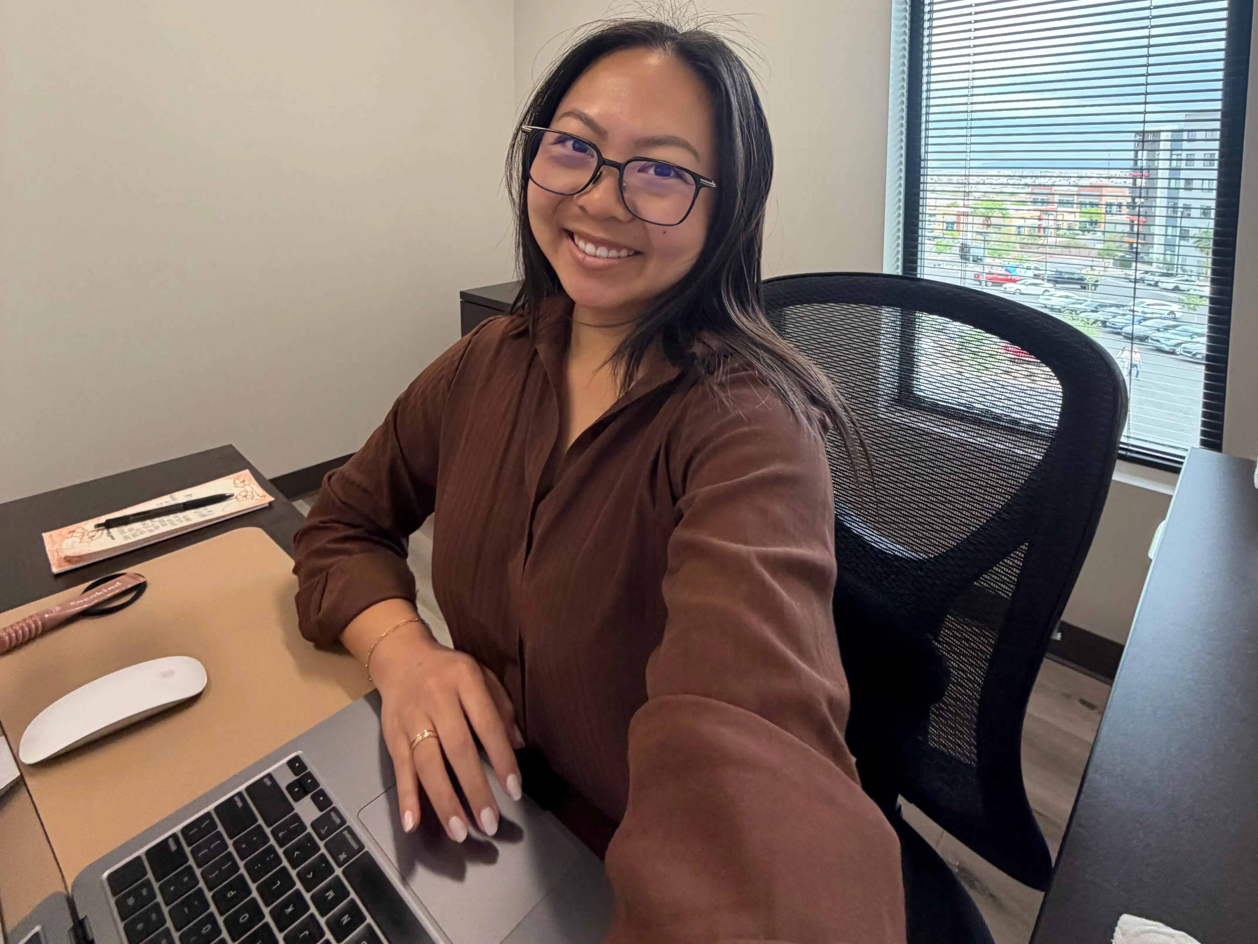 A young woman wearing glasses sitting at her computer