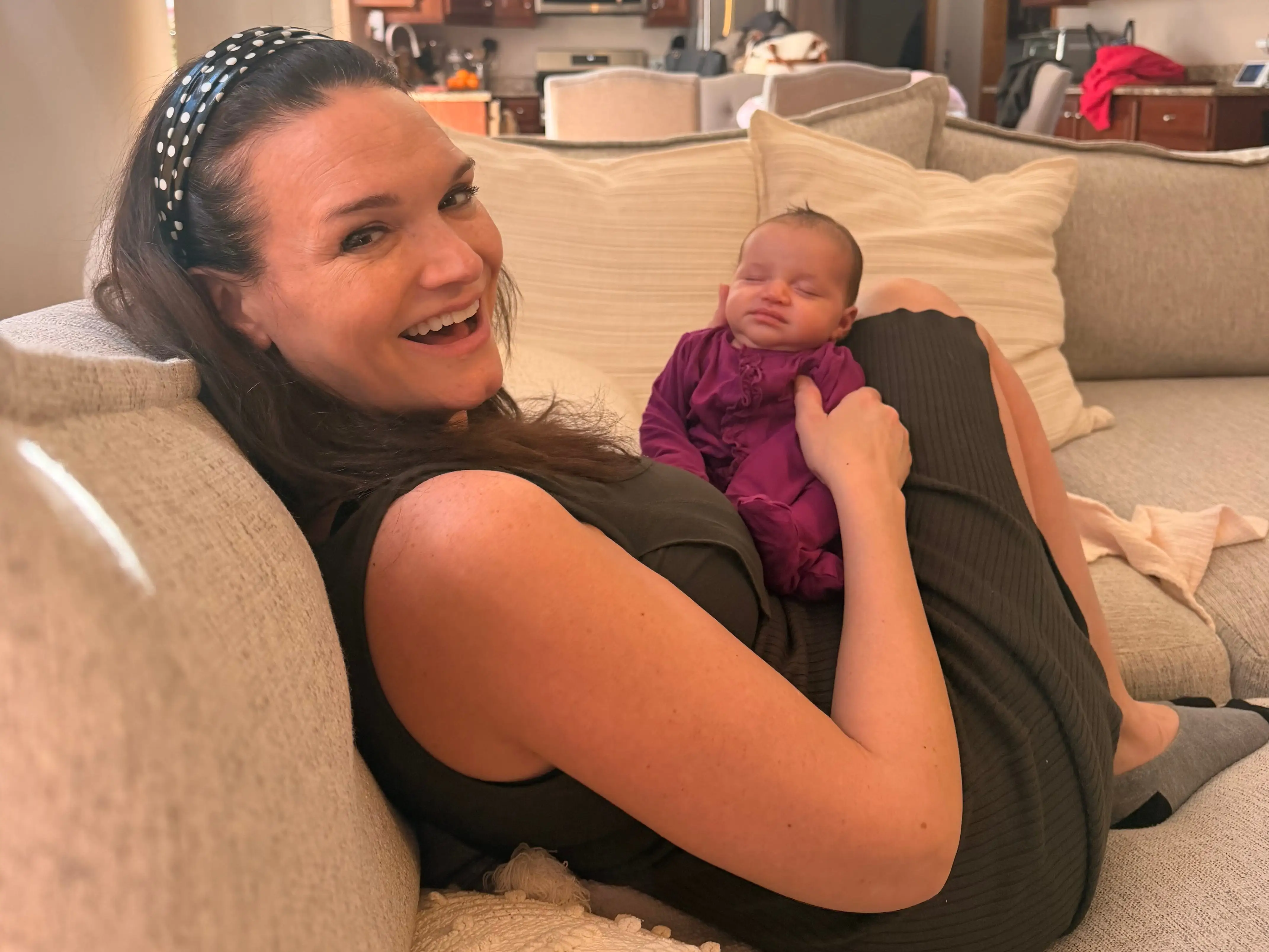 A mom relaxing on a couch with her new baby