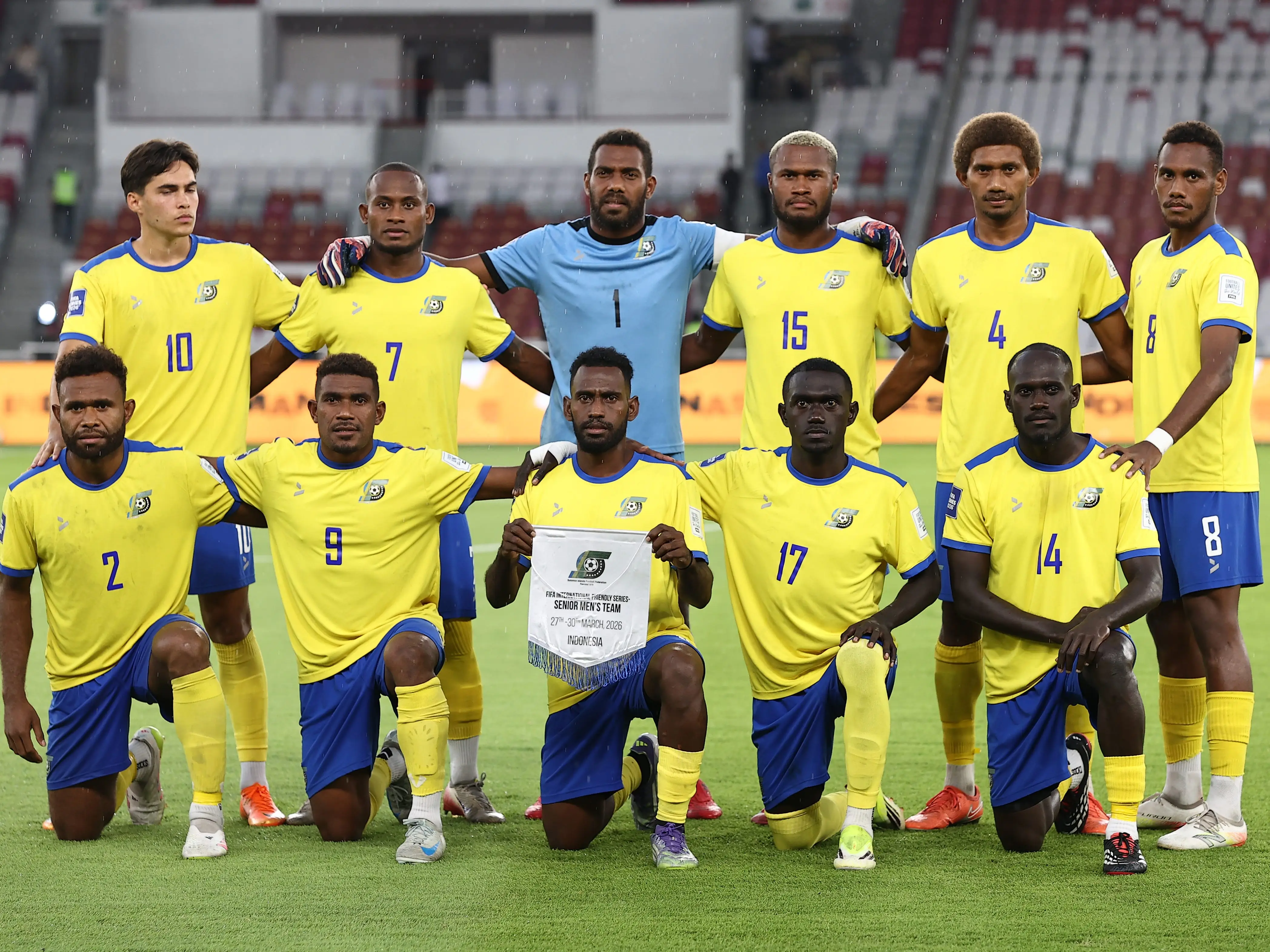 Players of the Solomon Islands men's national soccer team kneeling and standing for a photo.