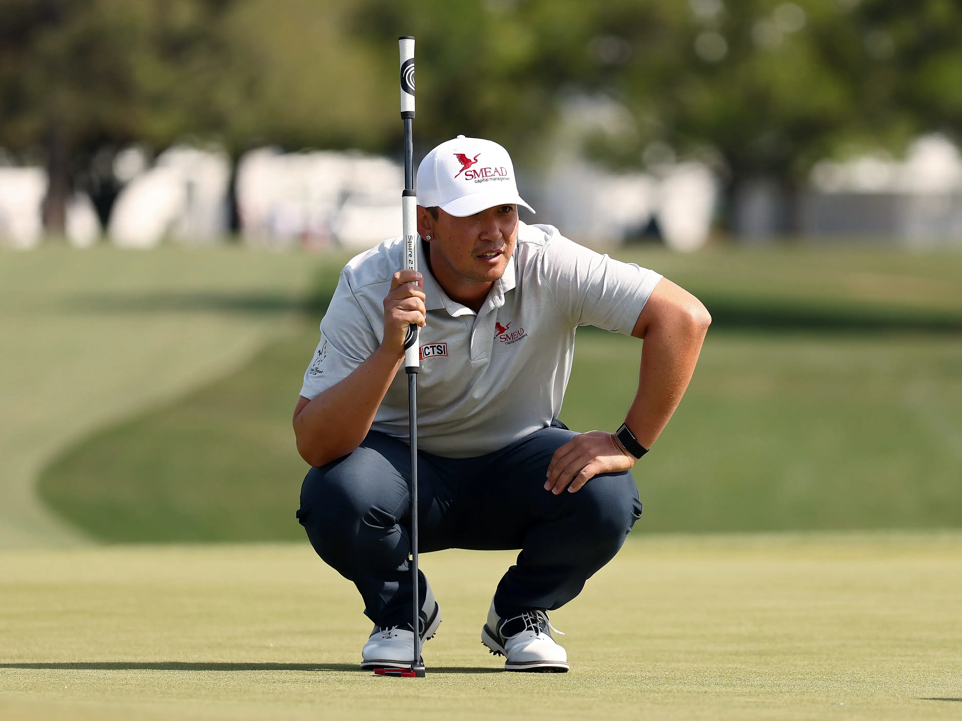 Rico Hoey of the Philippines squatting with a putter.