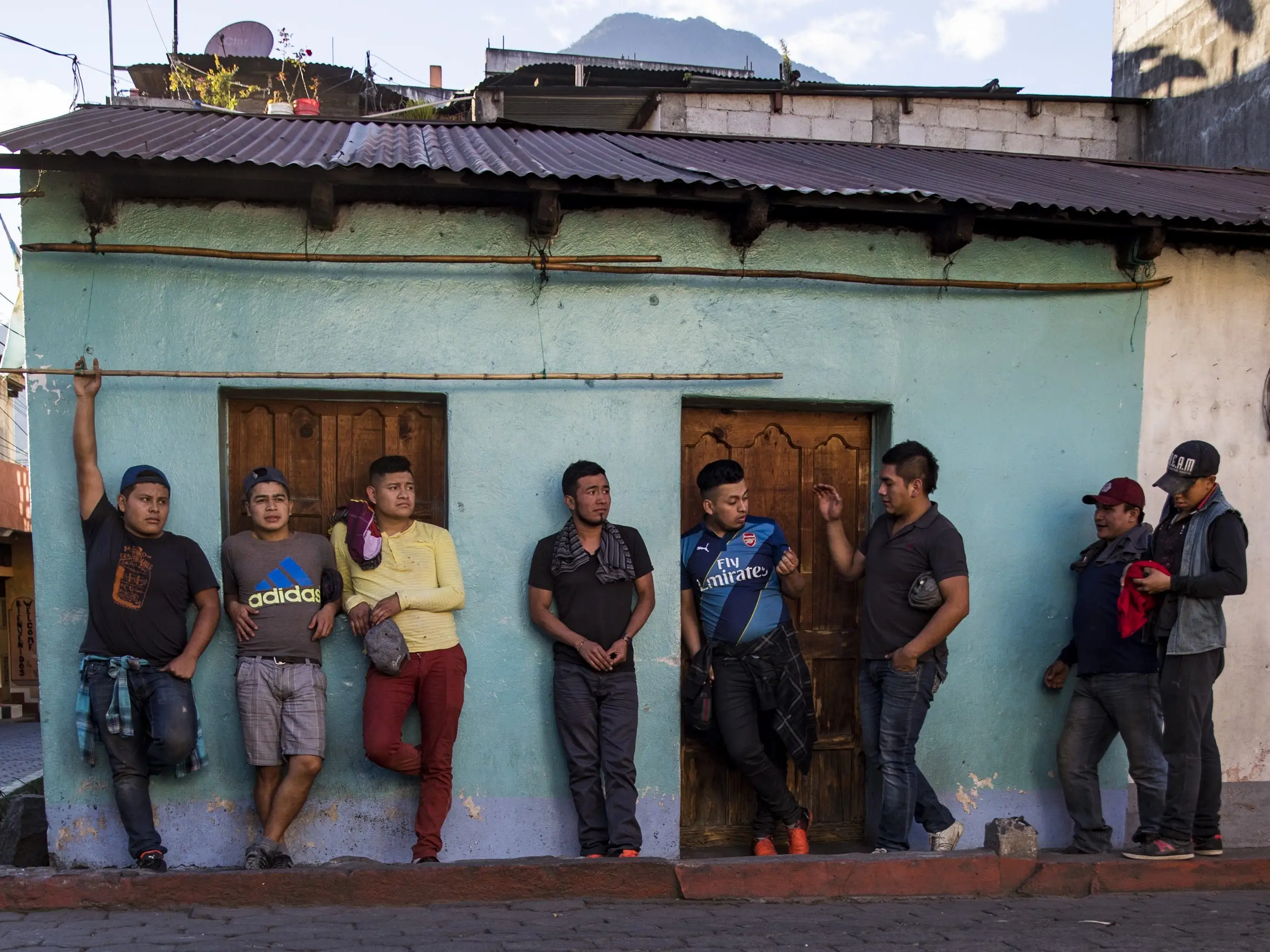 A group of eight men talk in front of a building in Lake Atitlan, Guatemala.