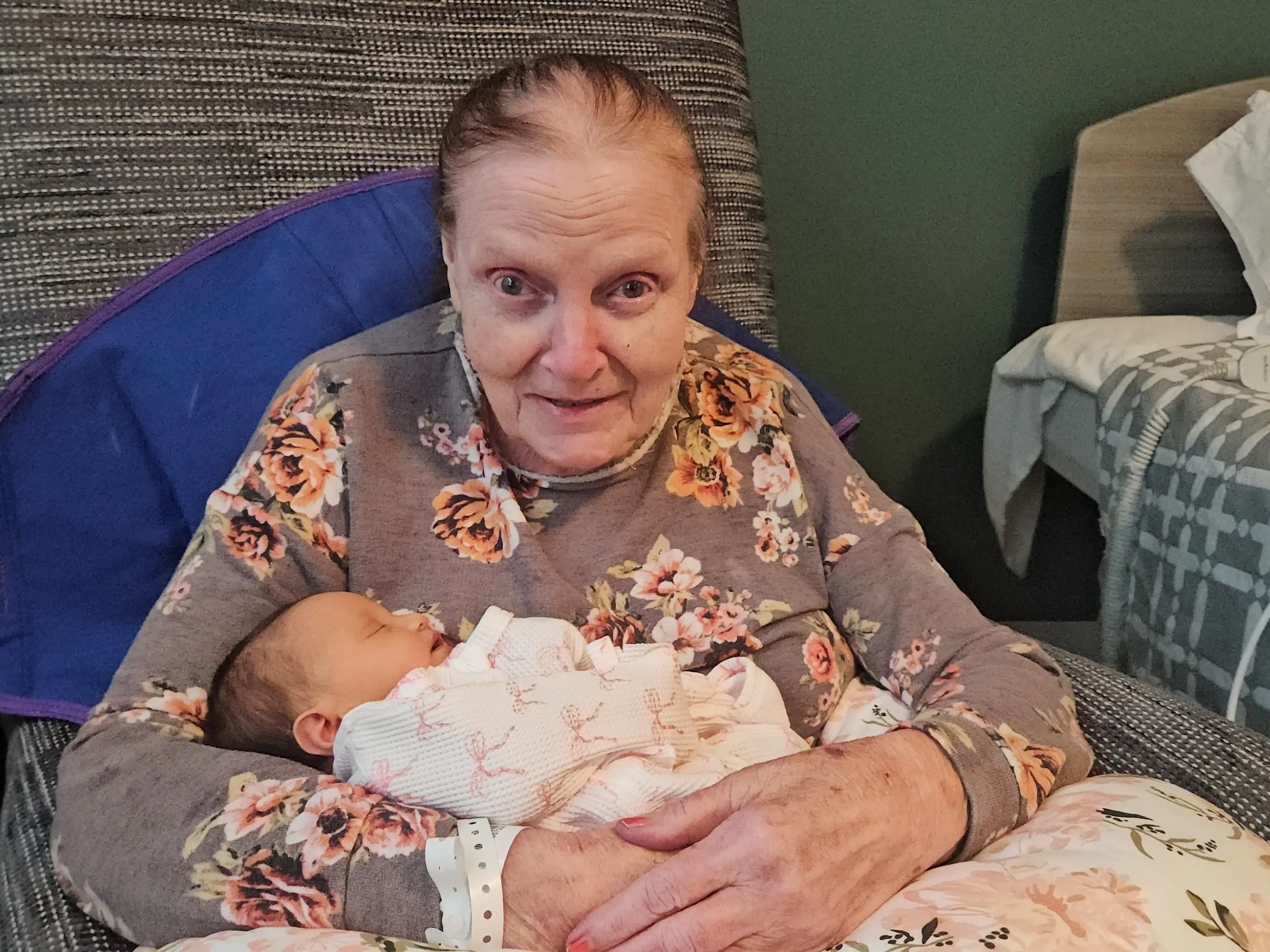 A senior woman cradling a baby on a cushion