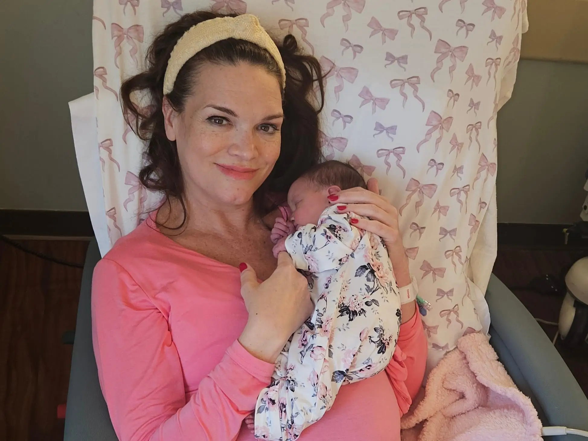 A mom and her sleeping baby daughter are sitting in a chair
