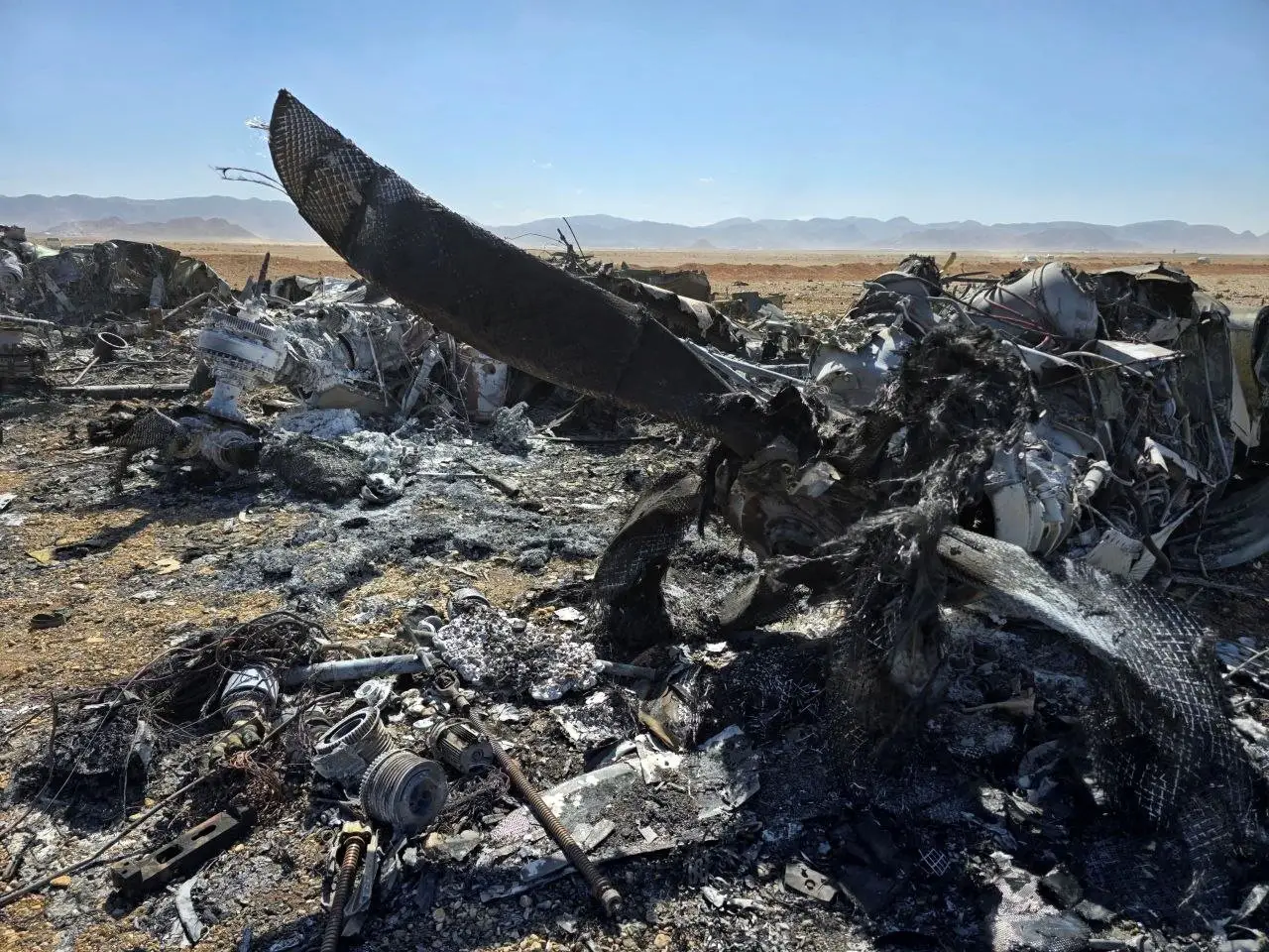 Plane wreckage sticks out of the desert.