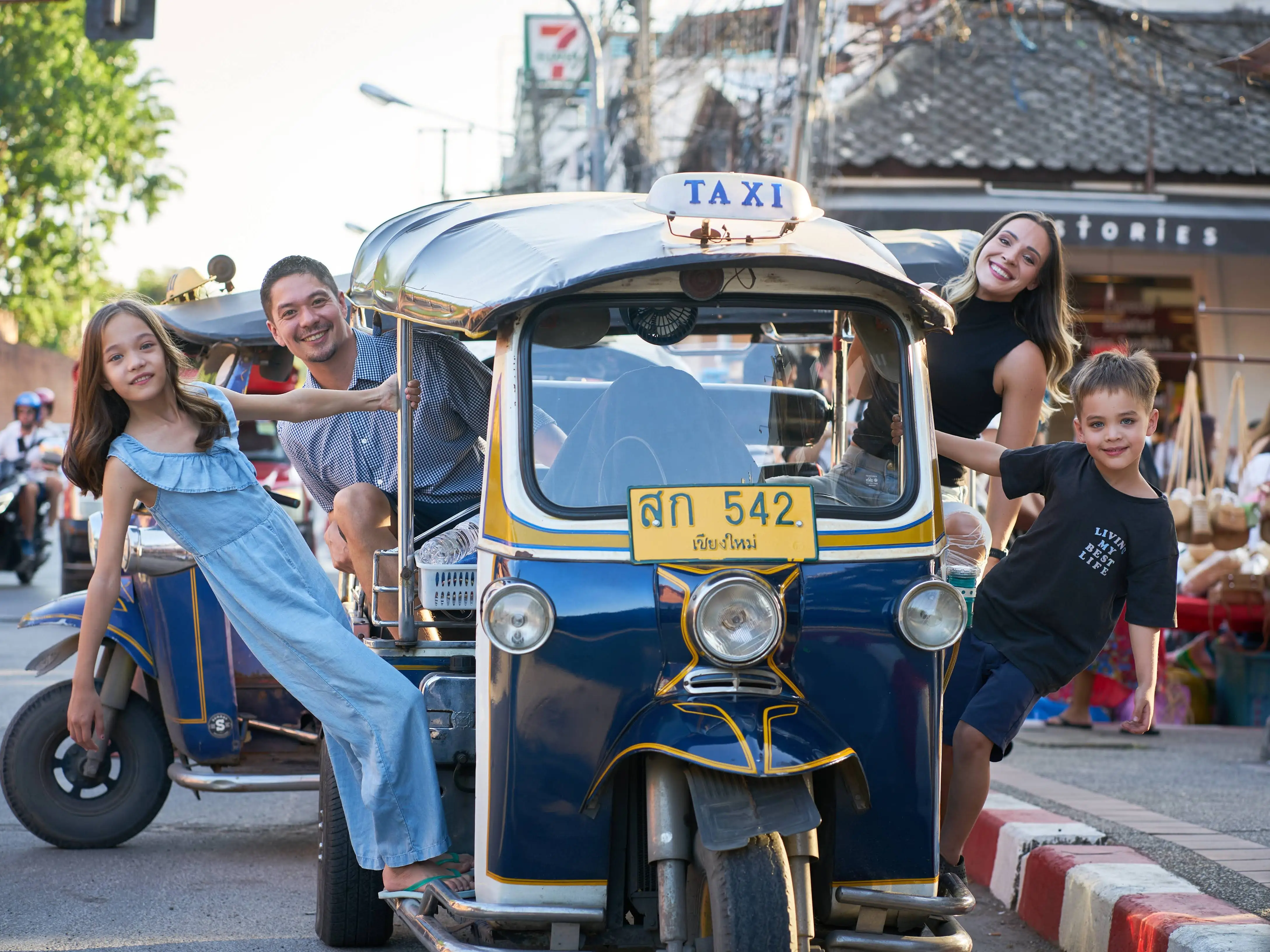 A family posing for a photo in a taxi in Thailand.