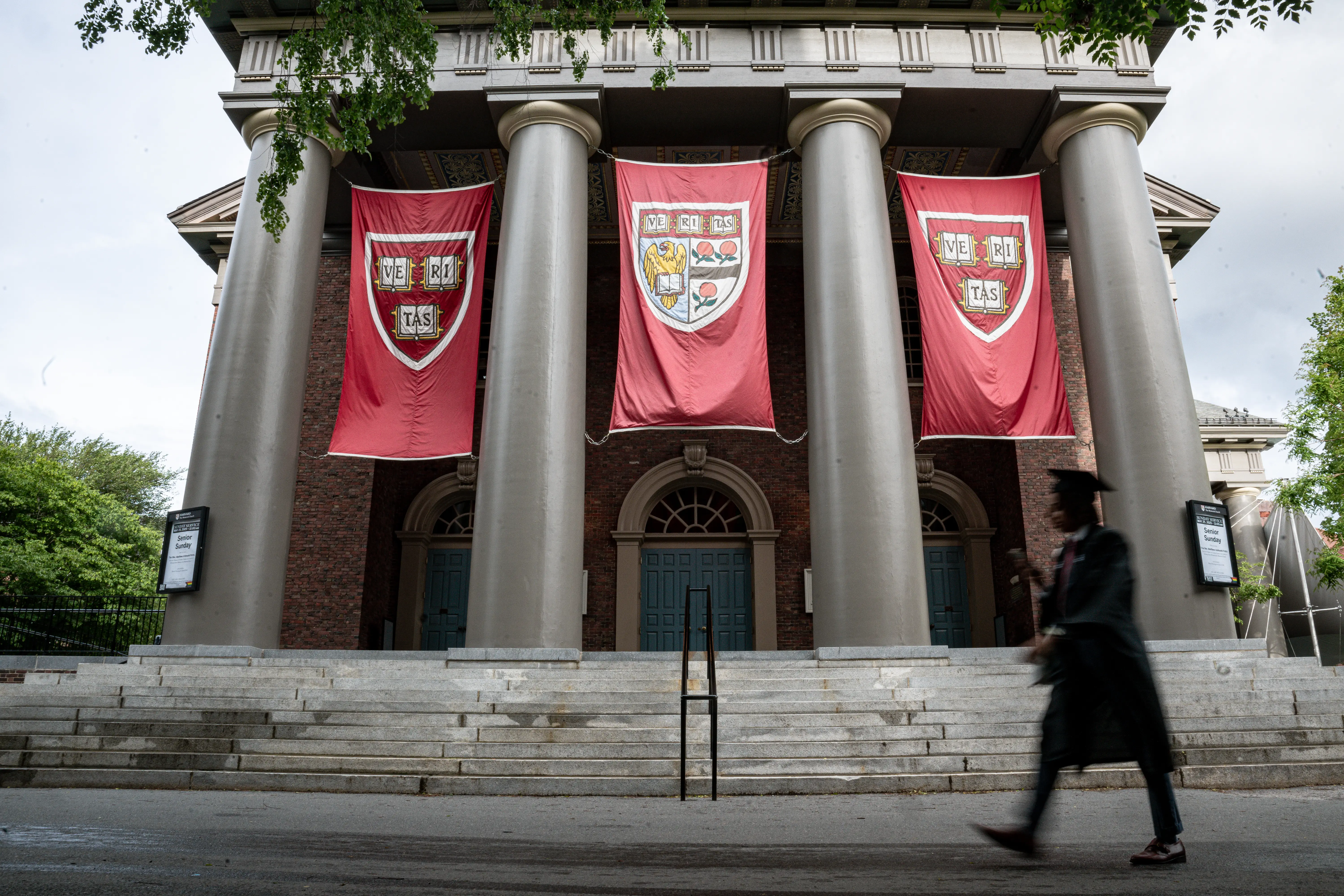 a student graduate walking past a building on harvard campus