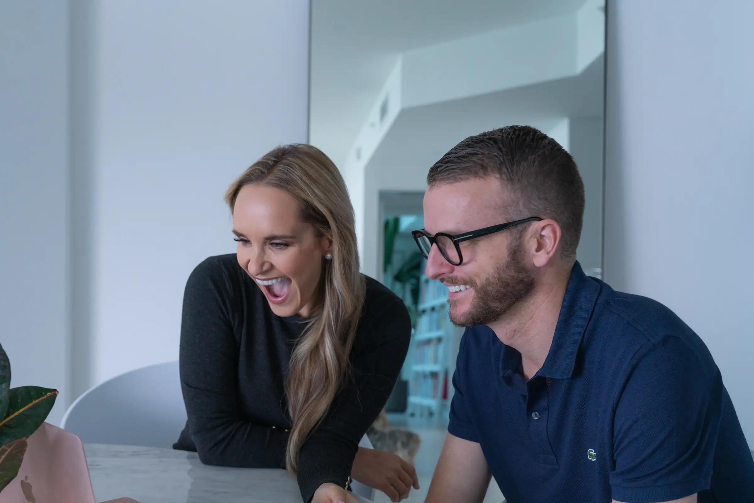 a married couple smiles at a laptop