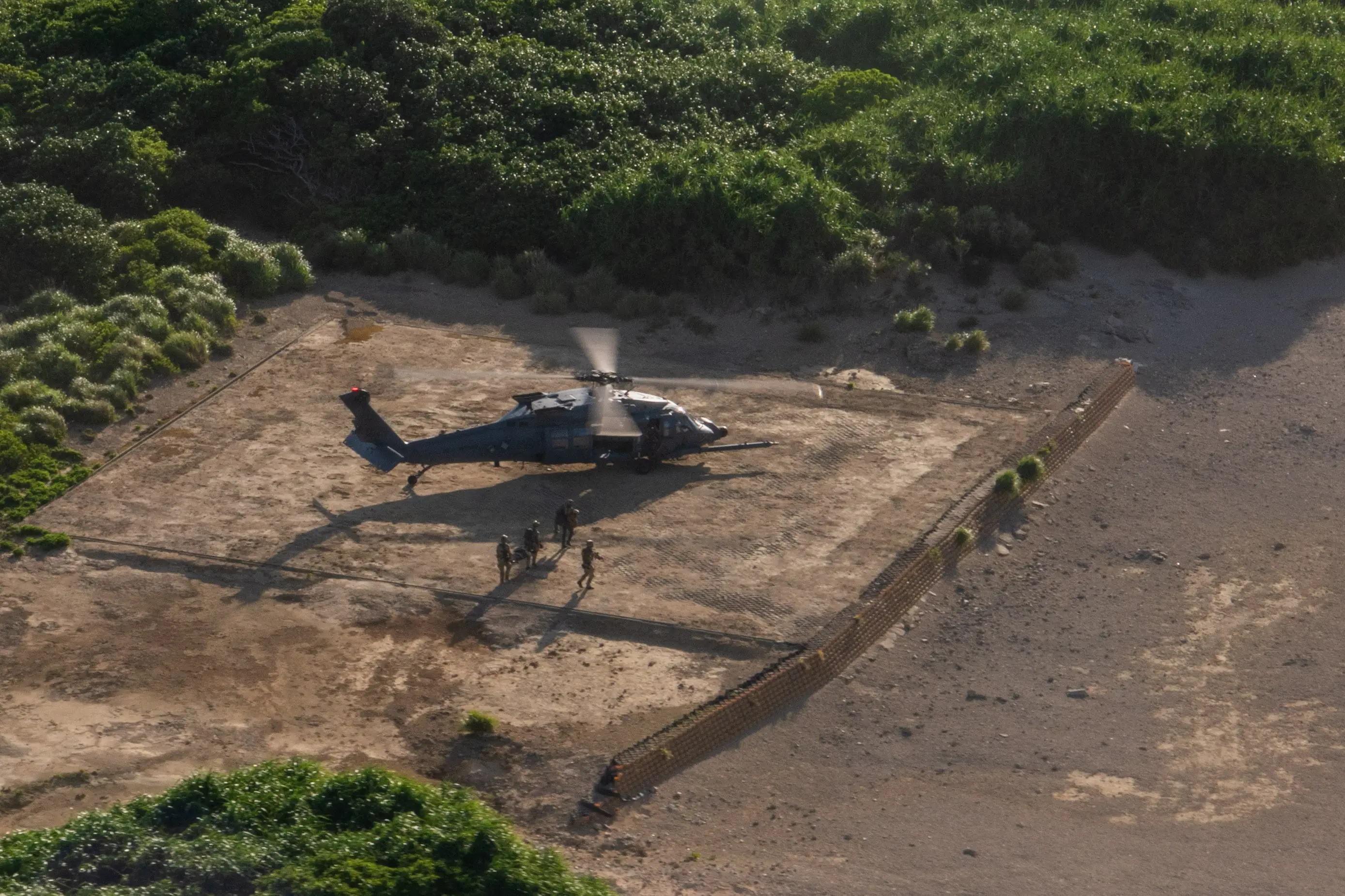 Air Force pararescuemen execute the recovery of isolated personnel while approaching an HH-60W Jolly Green II helicopter during training.