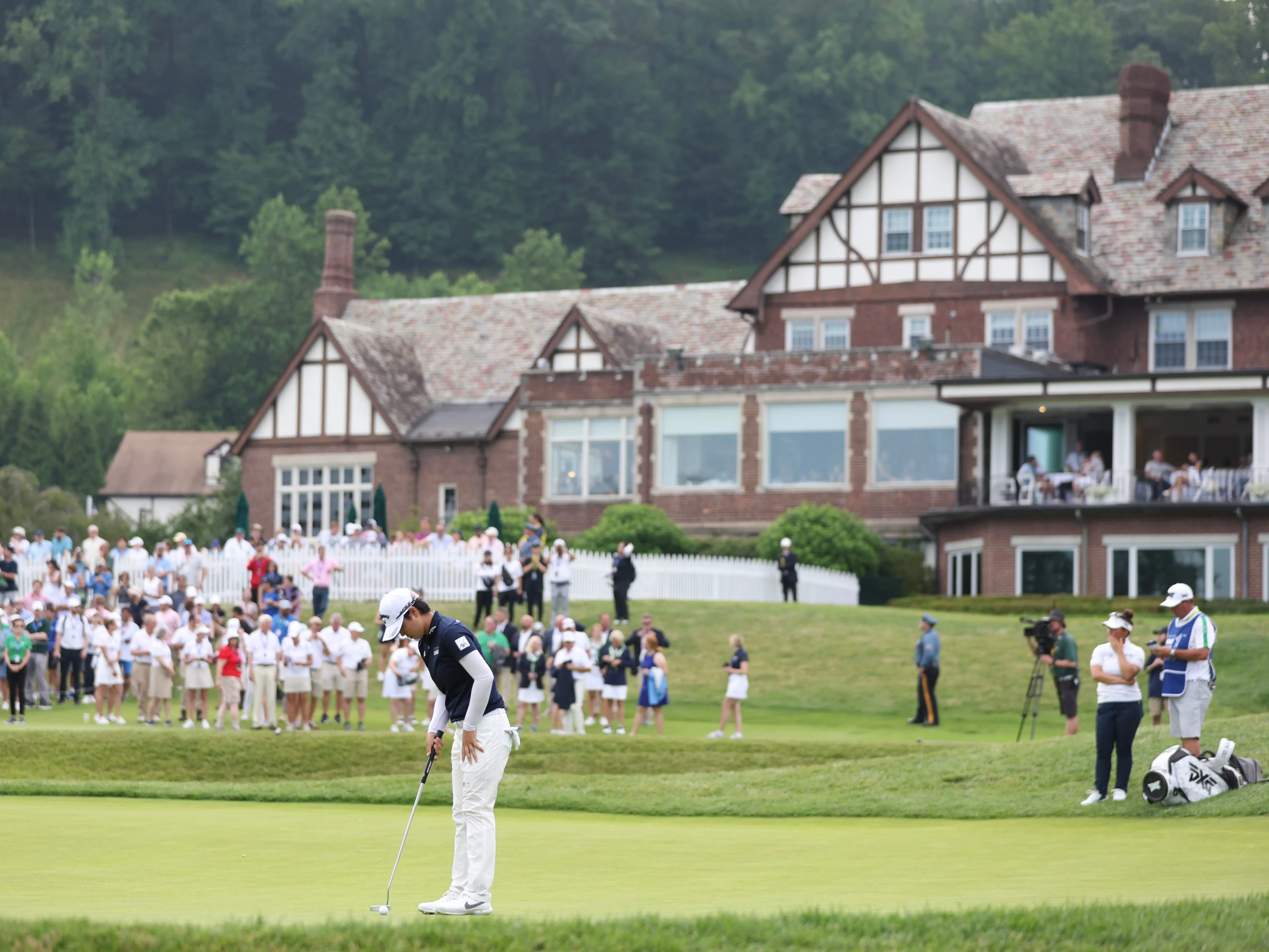 Yuka Saso of Japan putts the ball in front of a historic building at Baltusrol Golf Club.