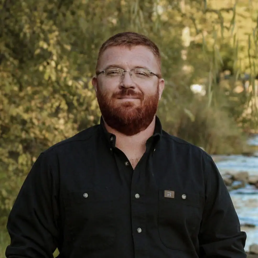 a man stands outside in nature to pose for a photo