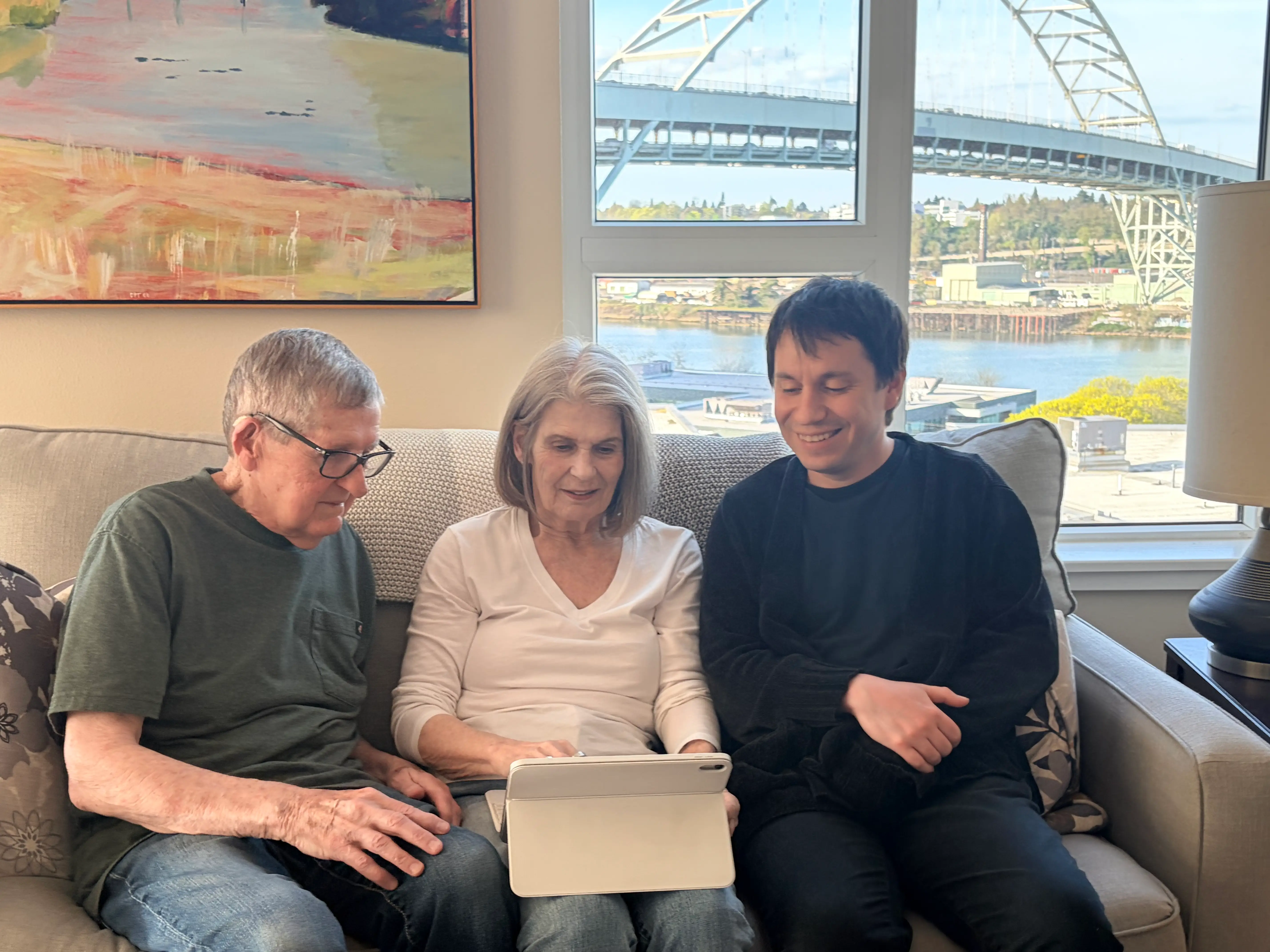 An older couple and a younger man are looking at an iPad.