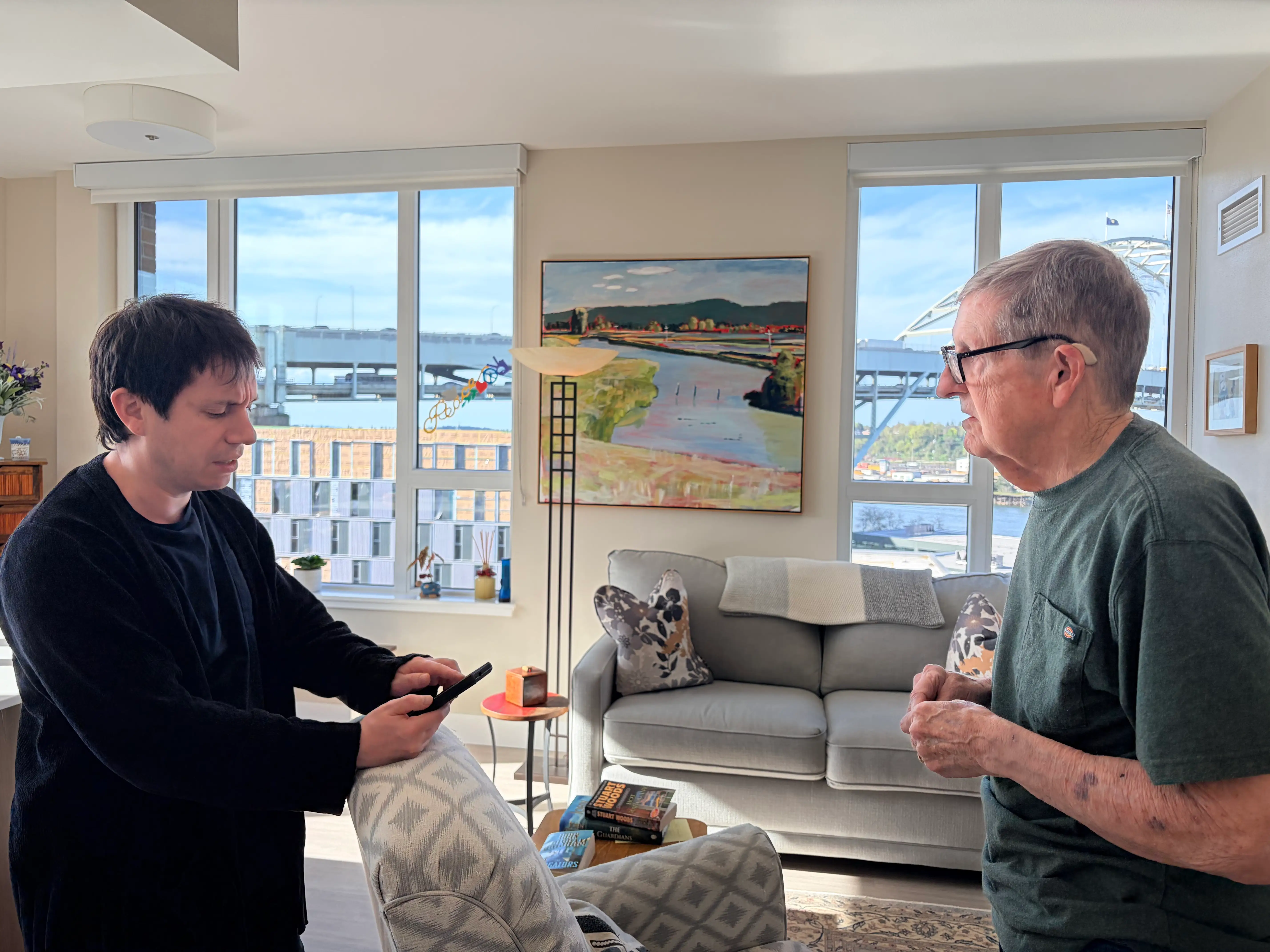 A man is talking to a senior while holding a cellphone.