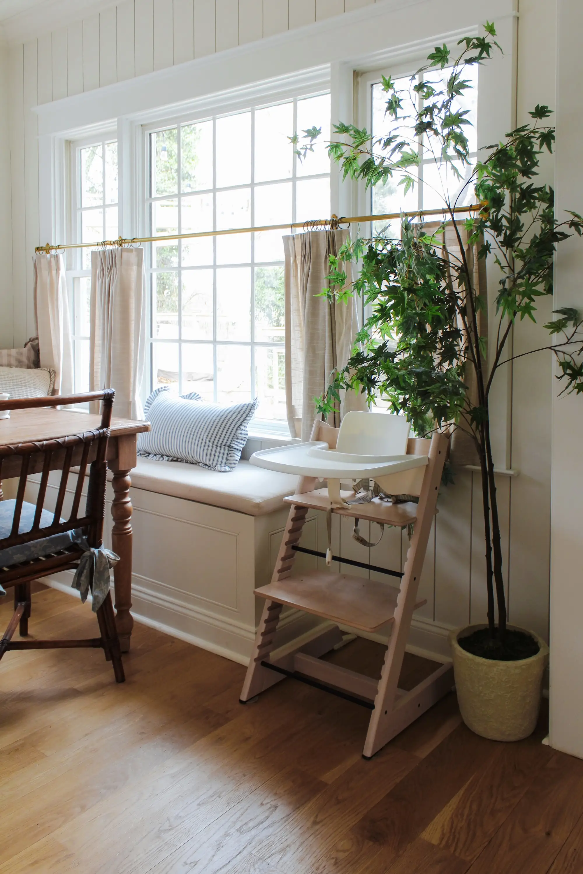 A large window with curtains and a bench seat under it.