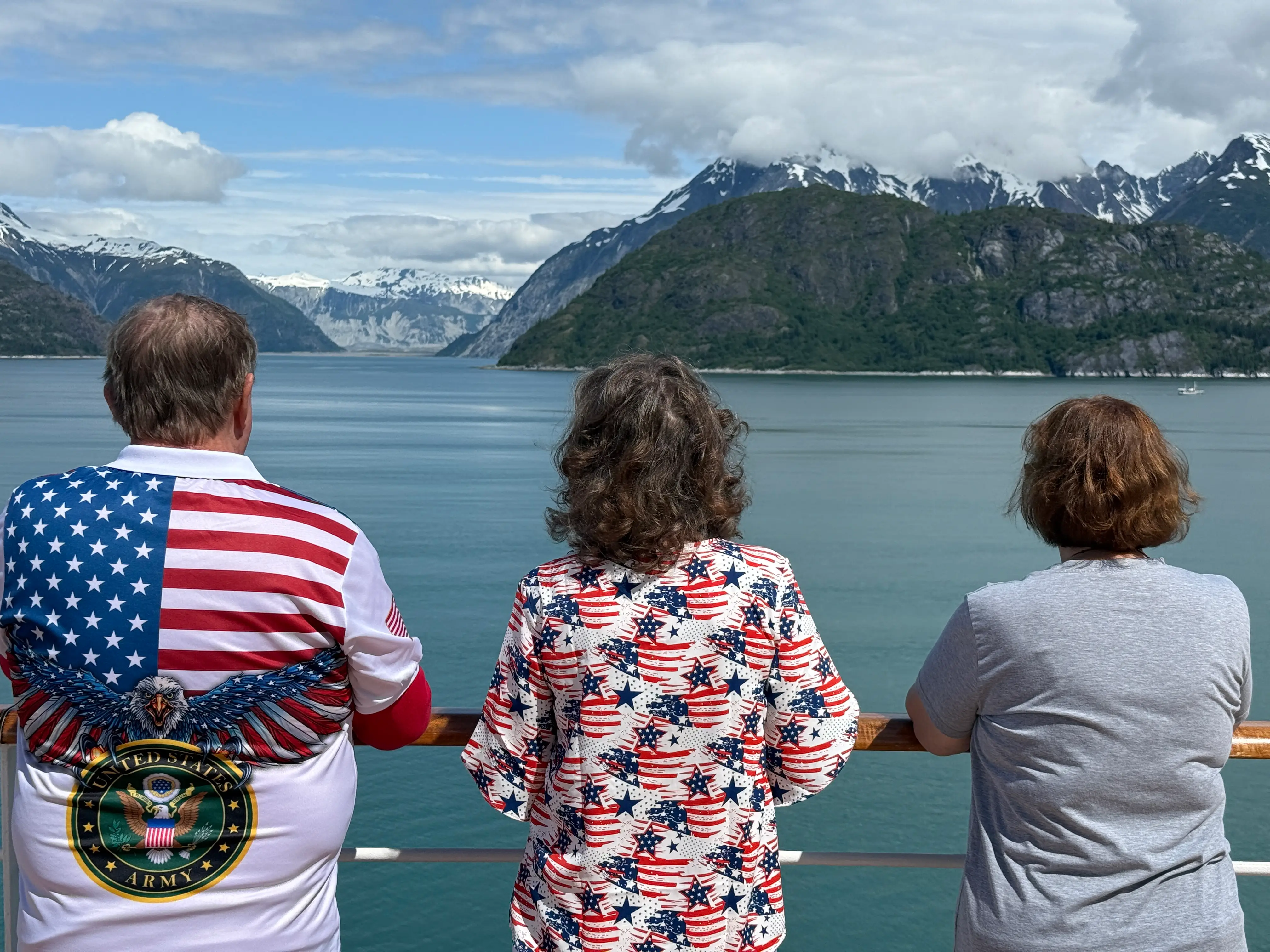 three people overlooking views from Alaskan cruise ship