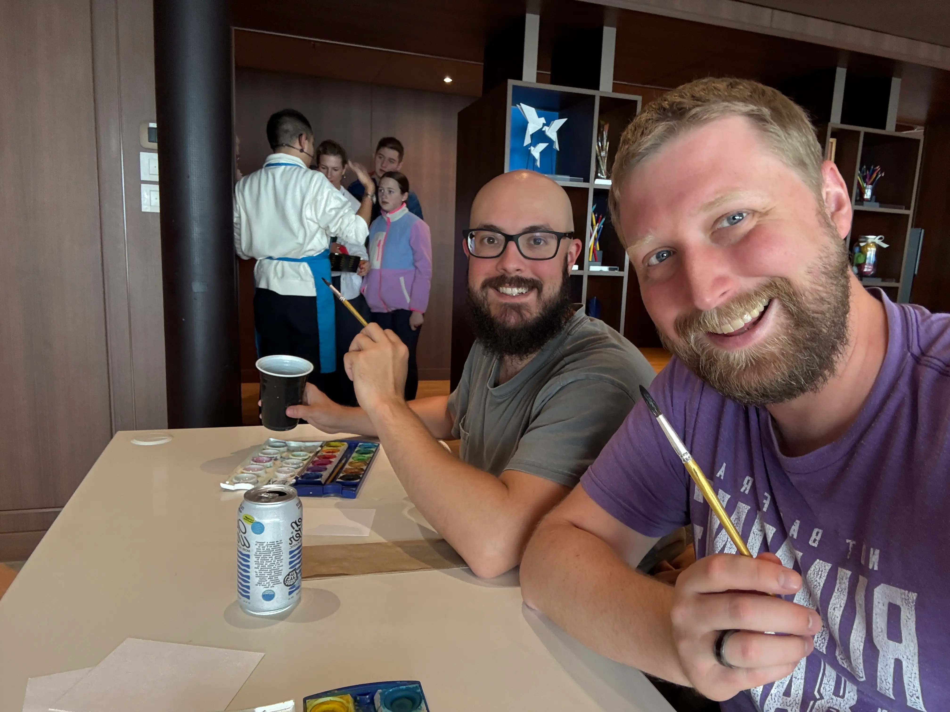 Two men smiling with paint brushes in hand
