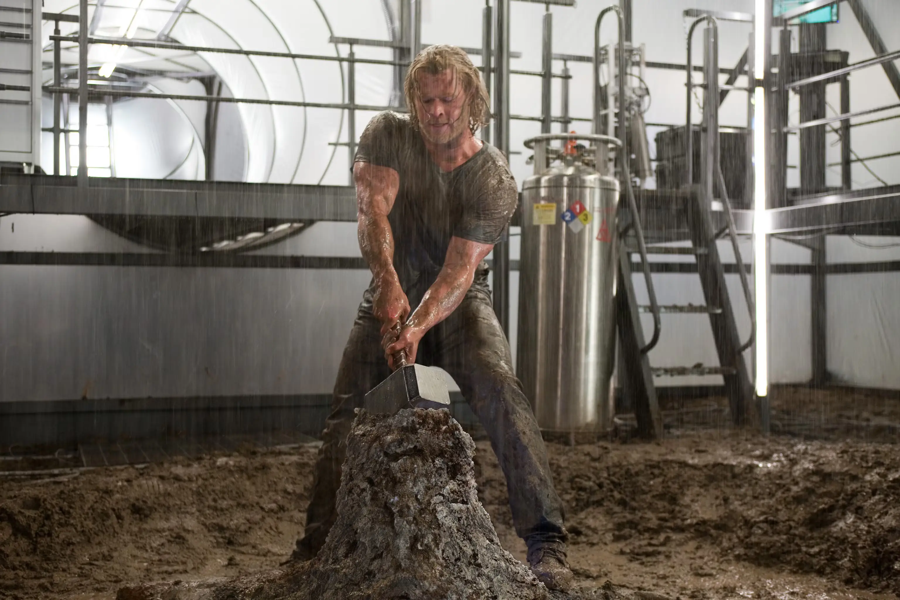 Chris Hemsworth in the rain trying to pull the hammer from the stone in Thor movie