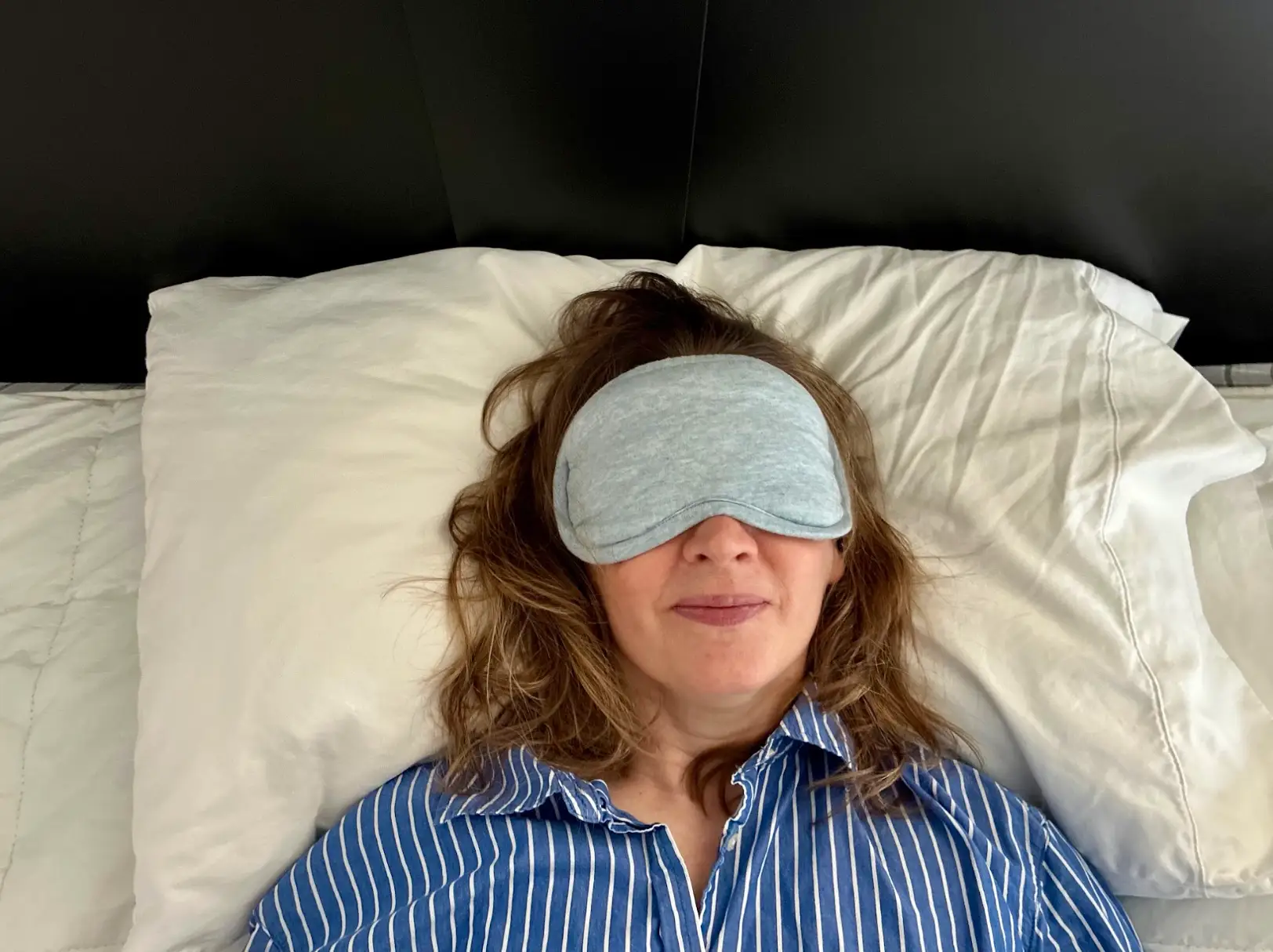 The writer resting on a hotel pillow with an eye mask covering her face.