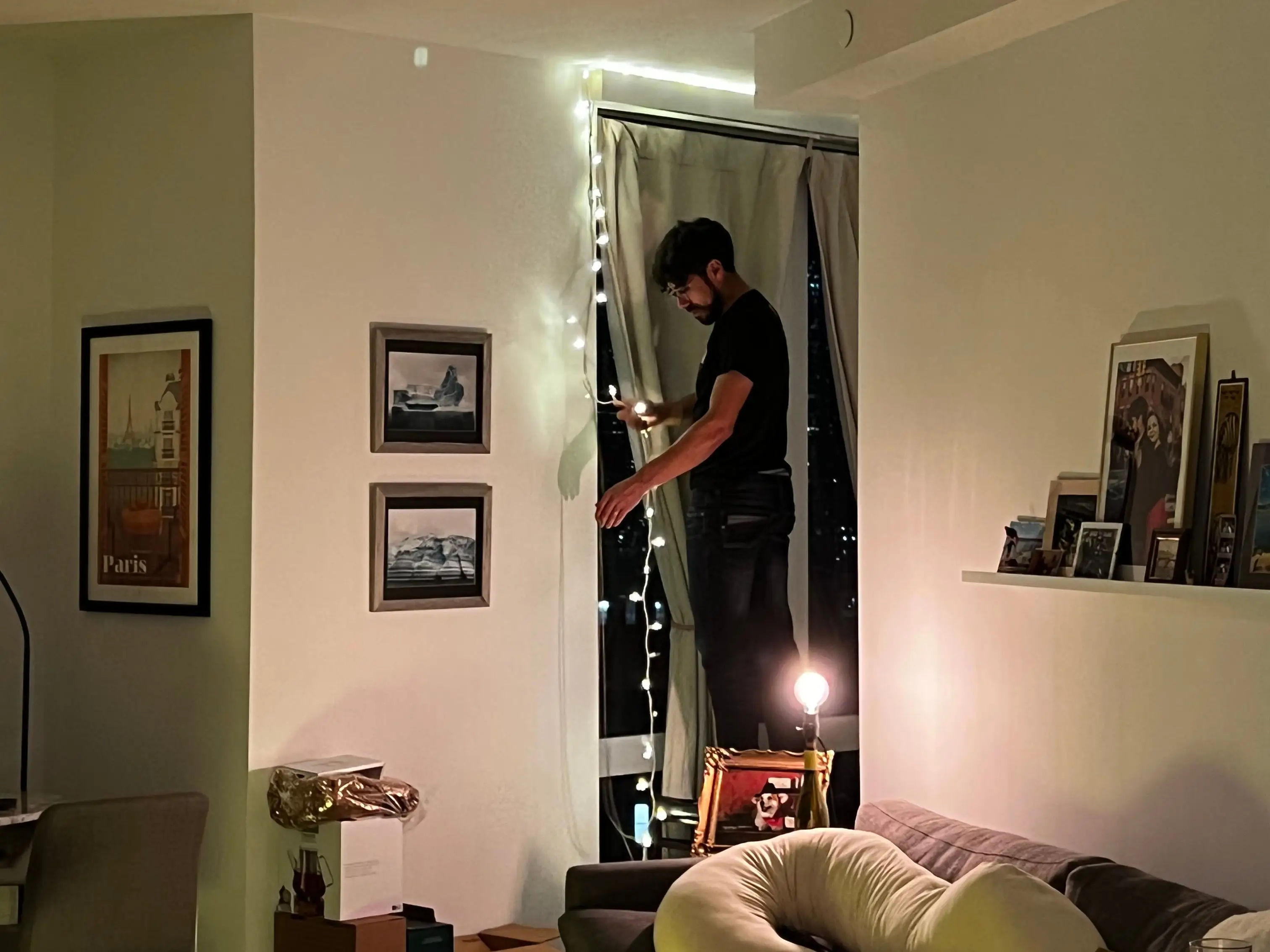 person hanging string lights in apartment window