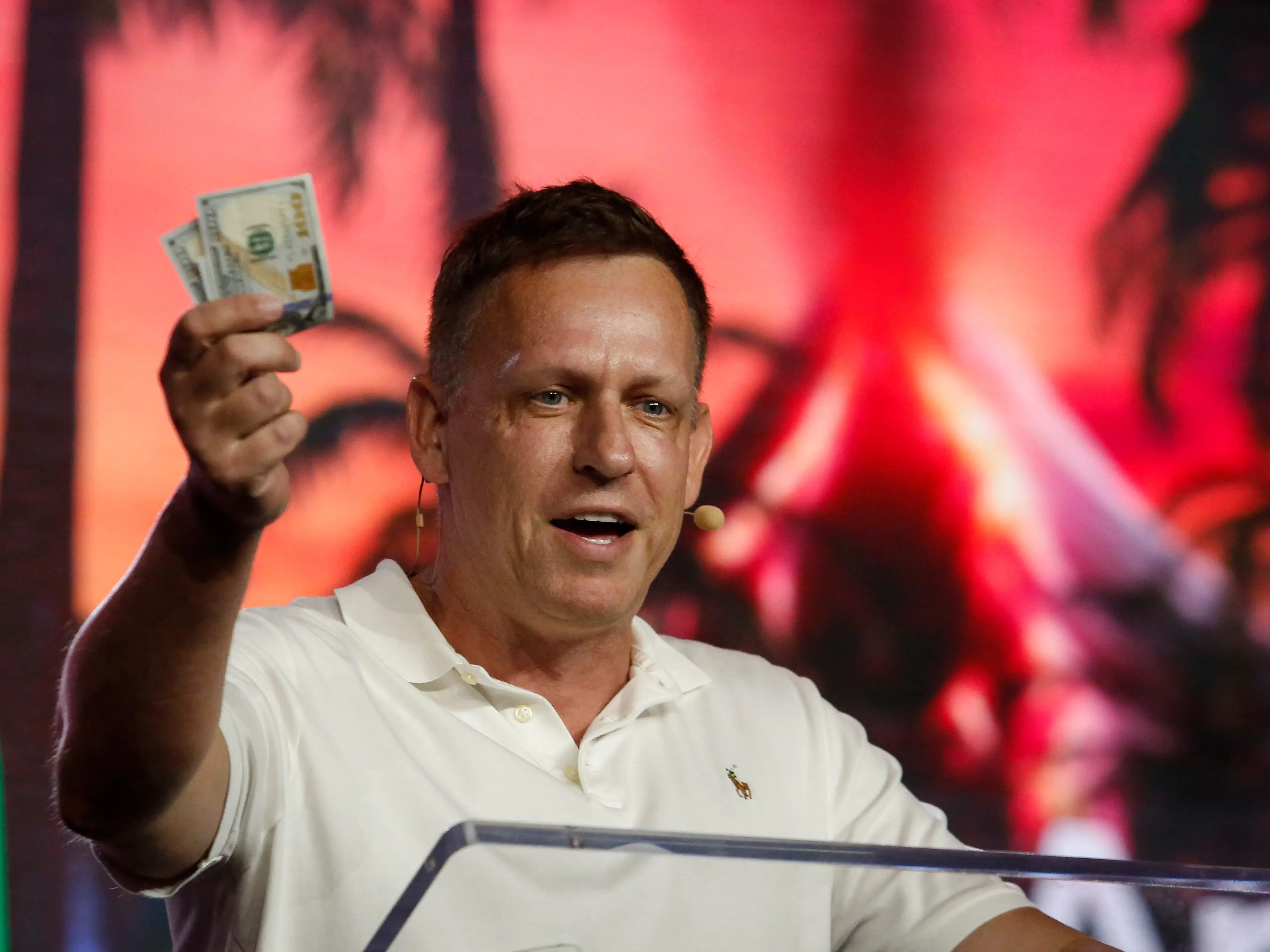 APRIL 7: Peter Thiel, co-founder of PayPal, Palantir Technologies, and Founders Fund, holds hundred dollar bills as he speaks during the Bitcoin 2022 Conference at Miami Beach Convention Center on April 7, 2022 in Miami, Florida. The worlds largest bitcoin conference runs from April 6-9, expecting over 30,000 people in