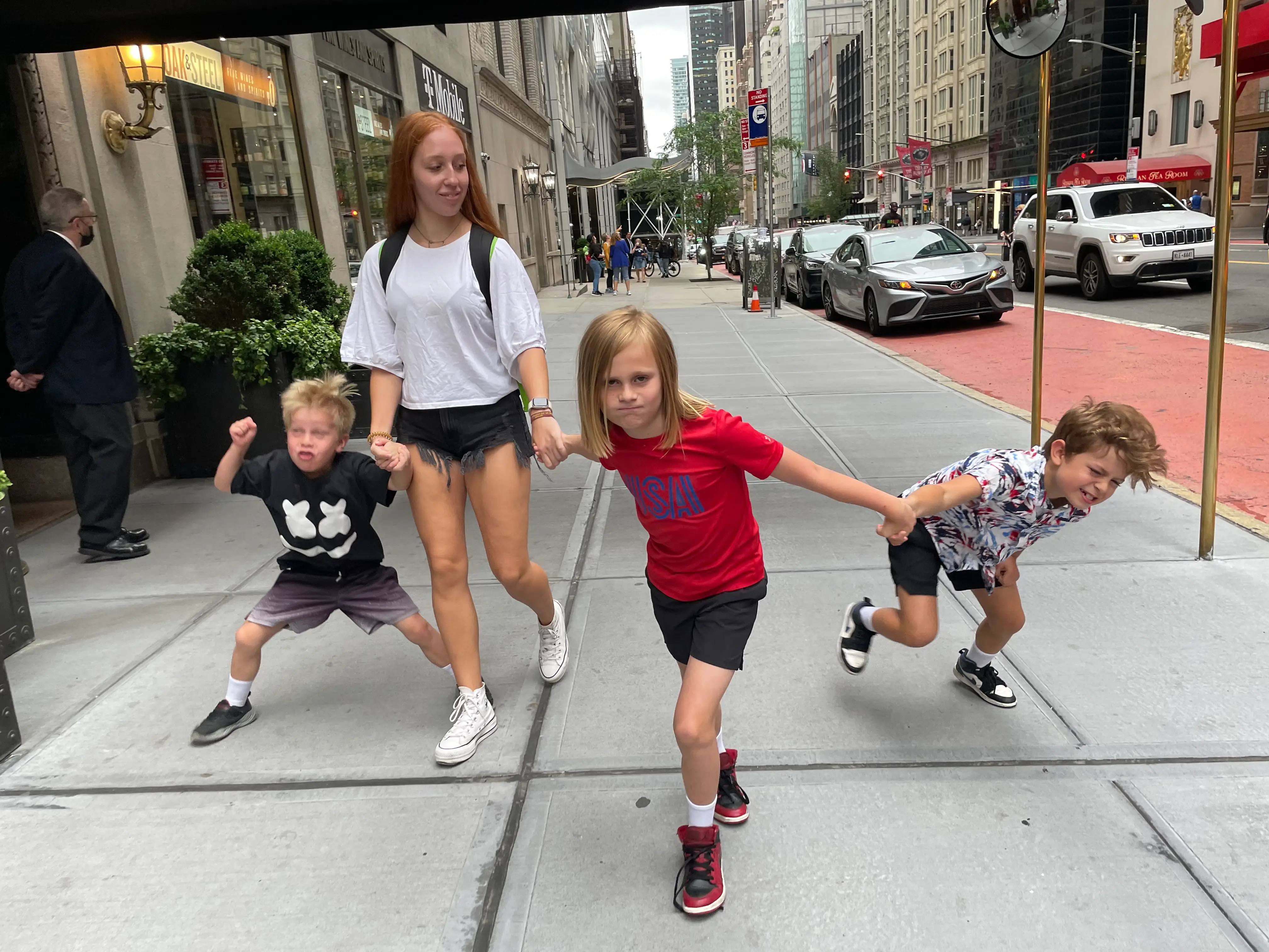 A young woman holding hands with three boys.