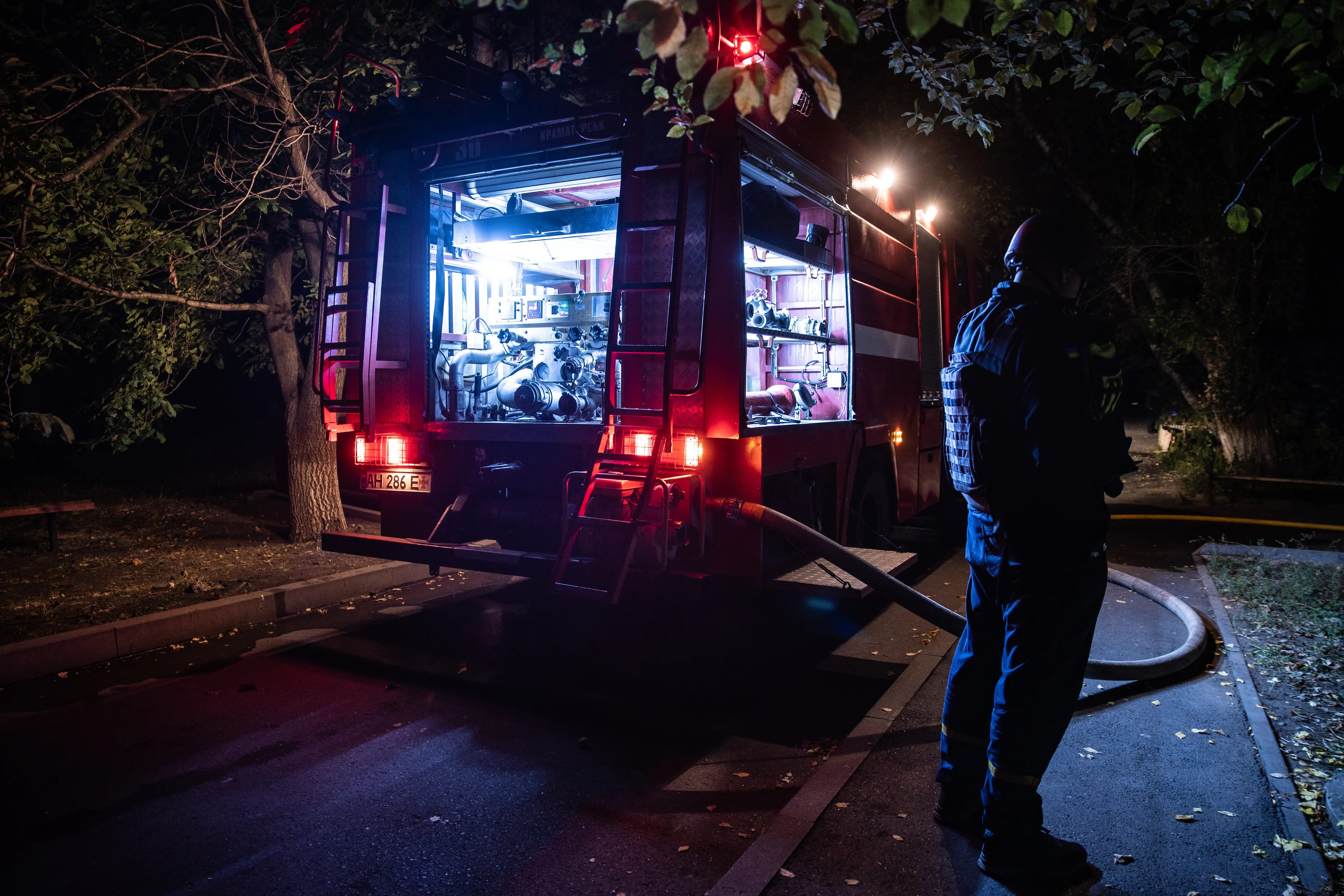 A Ukrainian man stands next to a fire truck at night.